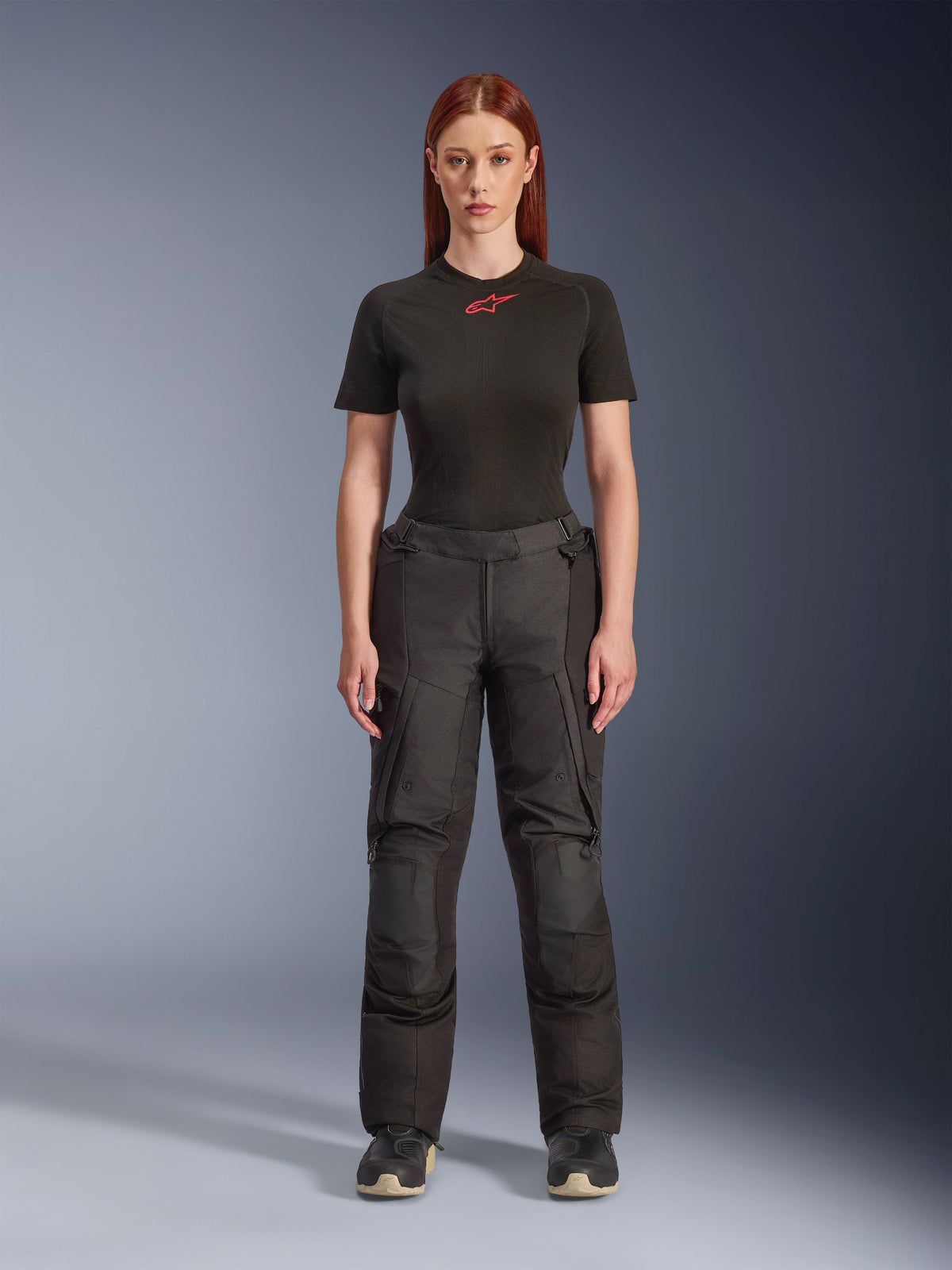 Pantalon Alpinestars Stella Andes V4 Drystar®, pantalon de moto touring aventure noir pour femme, porté par un mannequin avec un t-shirt noir Alpinestars, doté d'un design textile technique avec des poches cargo et des renforts aux genoux.