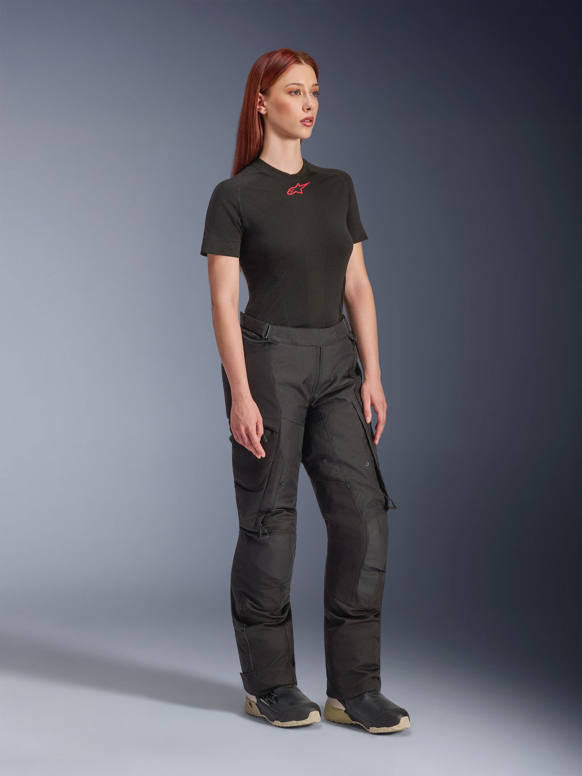Alpinestars Stella Andes V4 Drystar®, pantalon de moto pour femme, noir, porté avec un t-shirt noir à manches courtes avec logo rouge et des chaussures techniques, design adventure touring avec panneaux renforcés et zips de ventilation, vue de trois-quarts en pied