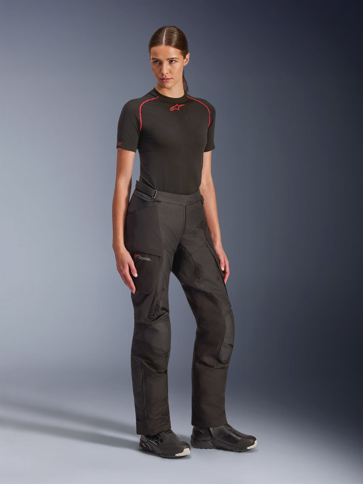Pantalon Alpinestars Stella Andes V4 Drystar®, noir, pantalon de moto touring aventure pour femme, porté avec une couche de base noire à manches courtes et des bottes de moto noires, doté de la technologie imperméable Drystar et de poches cargo