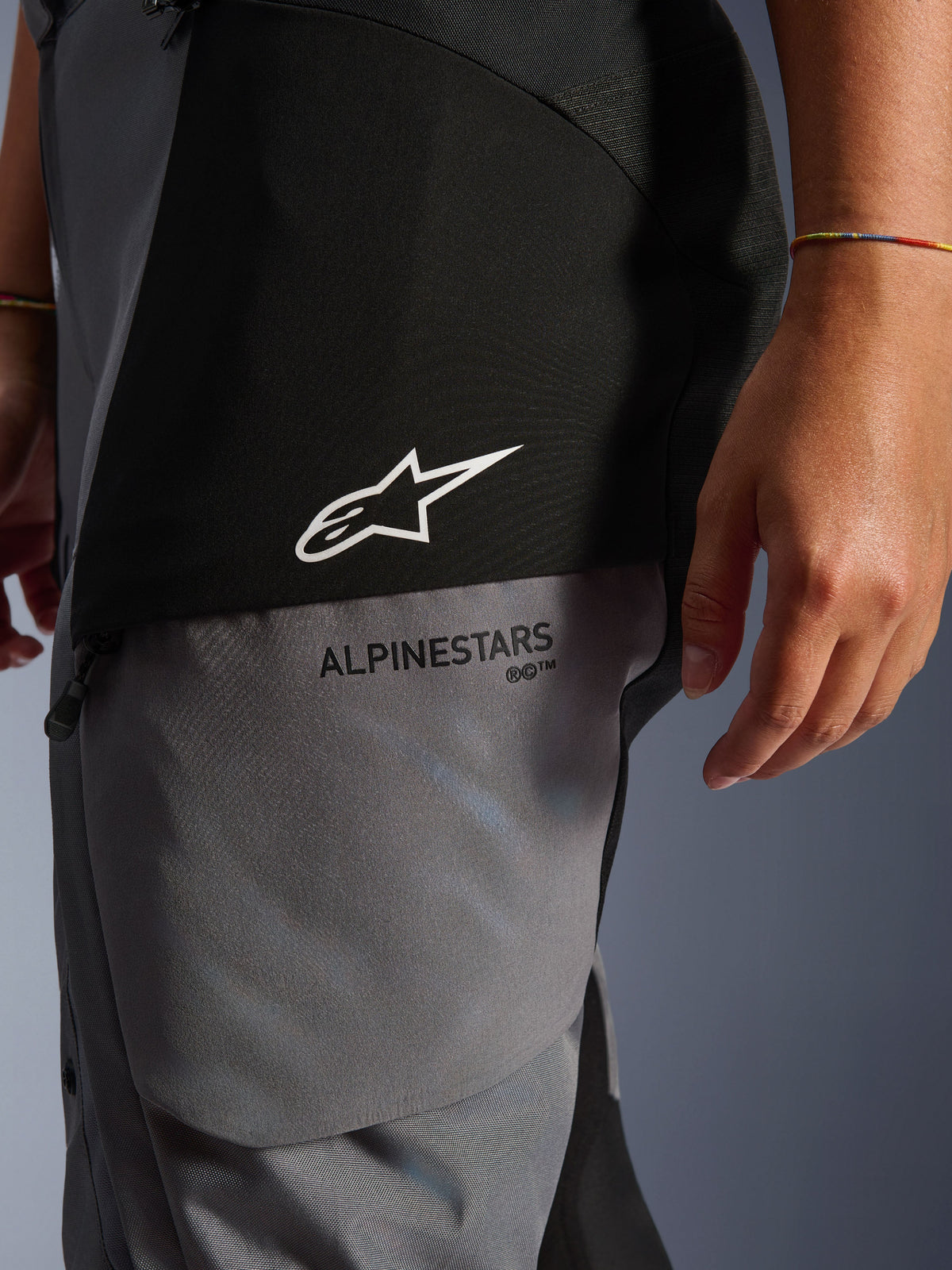 Pantalon Stella Andes V4 Drystar® pour femme, noir et gris foncé, gros plan sur le haut de la cuisse montrant le logo étoile blanc et le marquage Alpinestars noir, textile technique résistant pour le touring d'aventure