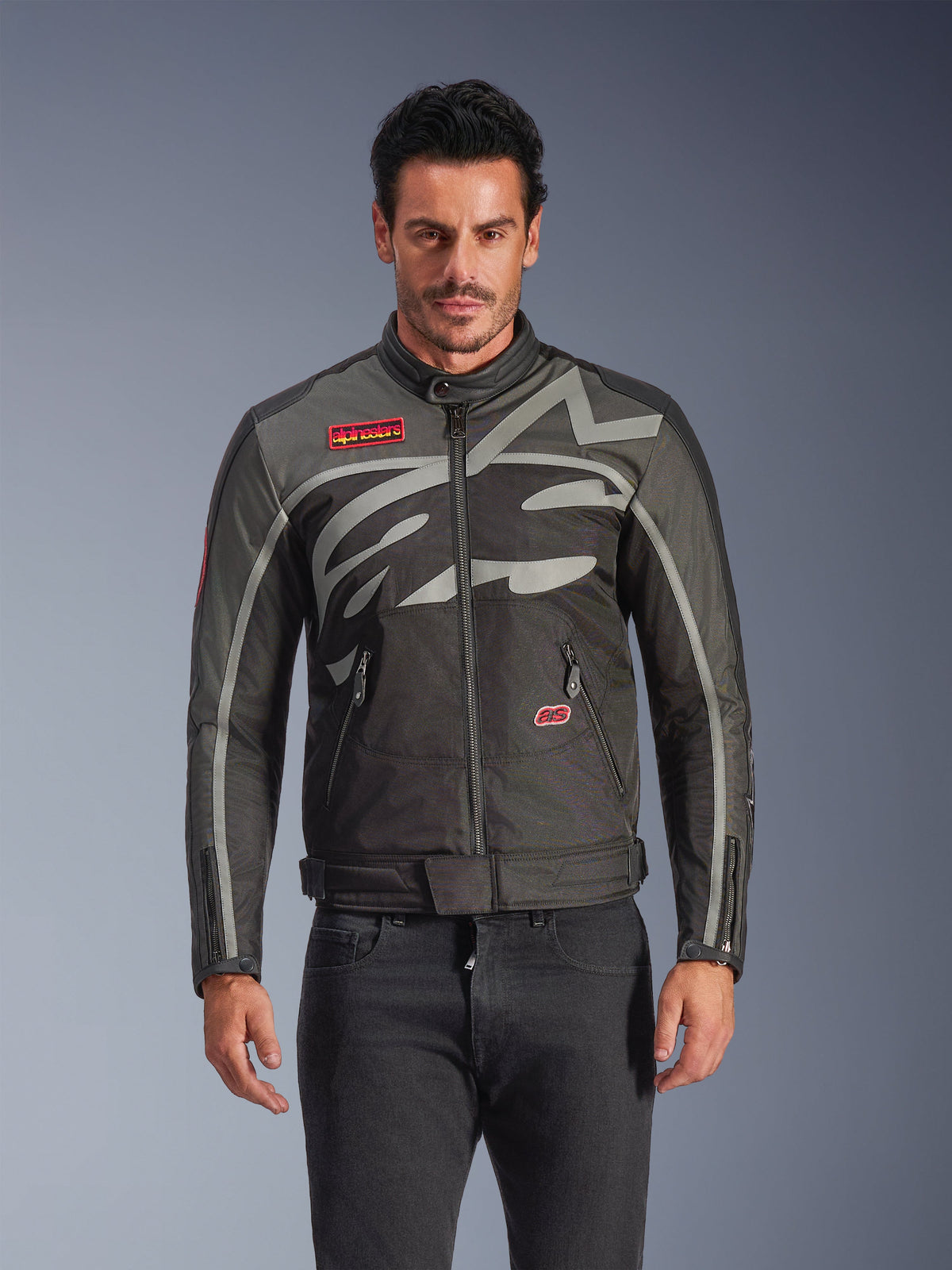 Veste Alpinestars Axton, veste de moto urbaine pour homme, noir et anthracite avec des touches de rouge, dotée d'un large motif graphique gris clair enveloppant, écussons avec logo rouge sur la poitrine et la poche, fermeture éclair frontale et poignets zippés, design de course d'inspiration vintage pour la conduite urbaine