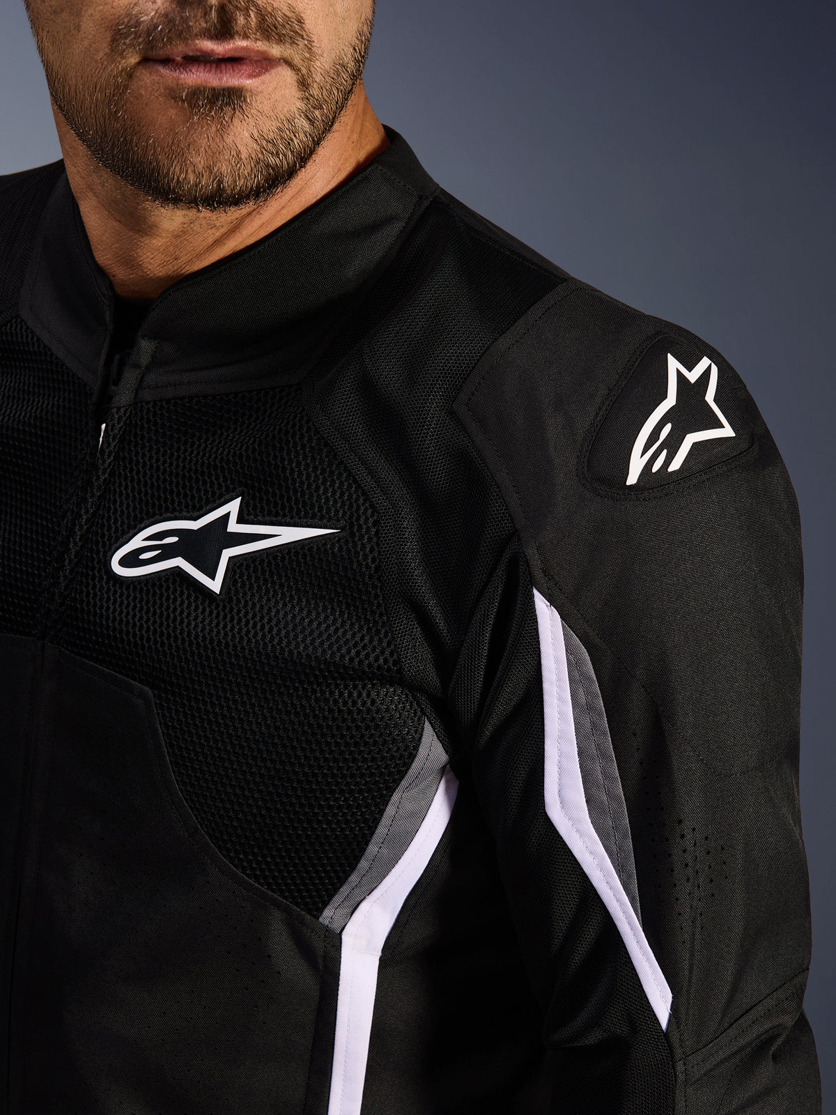Veste Alpinestars AST V3 Air, veste de moto en textile, noir, gris foncé et blanc, gros plan présentant des panneaux en maille, logo Alpinestars blanc sur la poitrine et l'épaule, et curseurs d'épaule externes DFS GP Lite Evo