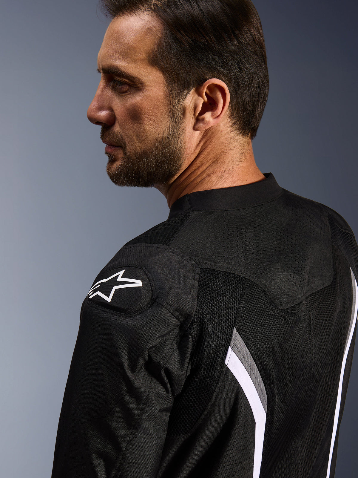 Veste Alpinestars AST V3 Air, veste de moto ventilée, noir, gris foncé et blanc, vue rapprochée de dos montrant le logo étoile blanc sur l'épaule et les panneaux en maille perforés au laser pour la ventilation.