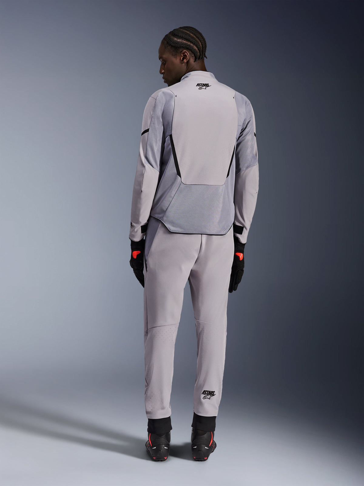 Veste Alpinestars Aeroshell Airflow, Gris moyen anthracite, vue de dos sur un mannequin, dotée de panneaux en maille technique et de zones de ventilation perforées au laser, portée avec un pantalon gris assorti et un équipement de moto noir, design à coupe sportive pour haute performance.