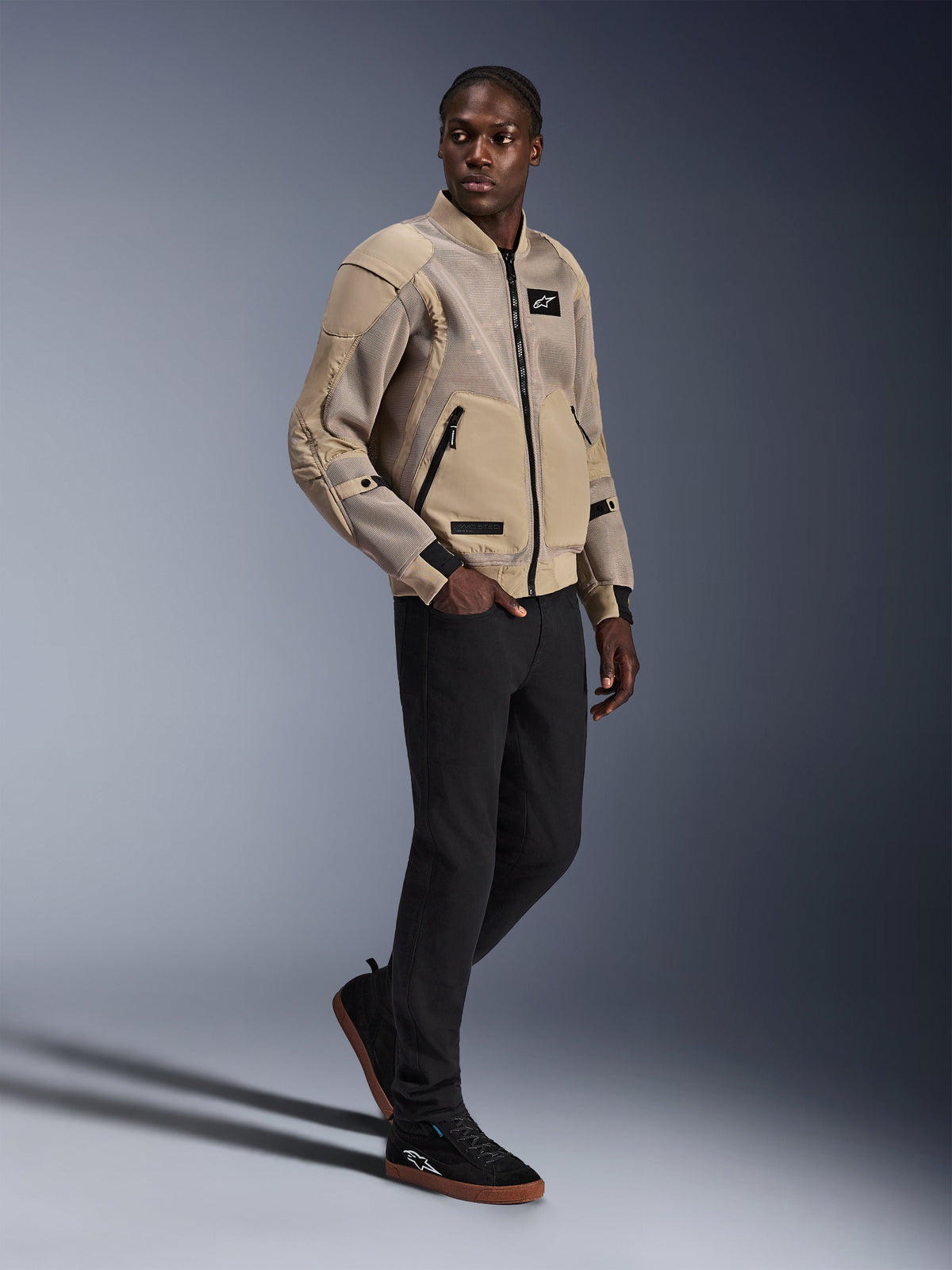 Alpinestars Flight Air Jacket, Urban Motorcycle Jacket, Aluminum color, worn by model with black pants and black sneakers, featuring 3D mesh ventilation panels and a bomber-style design, modern street style for urban riding.