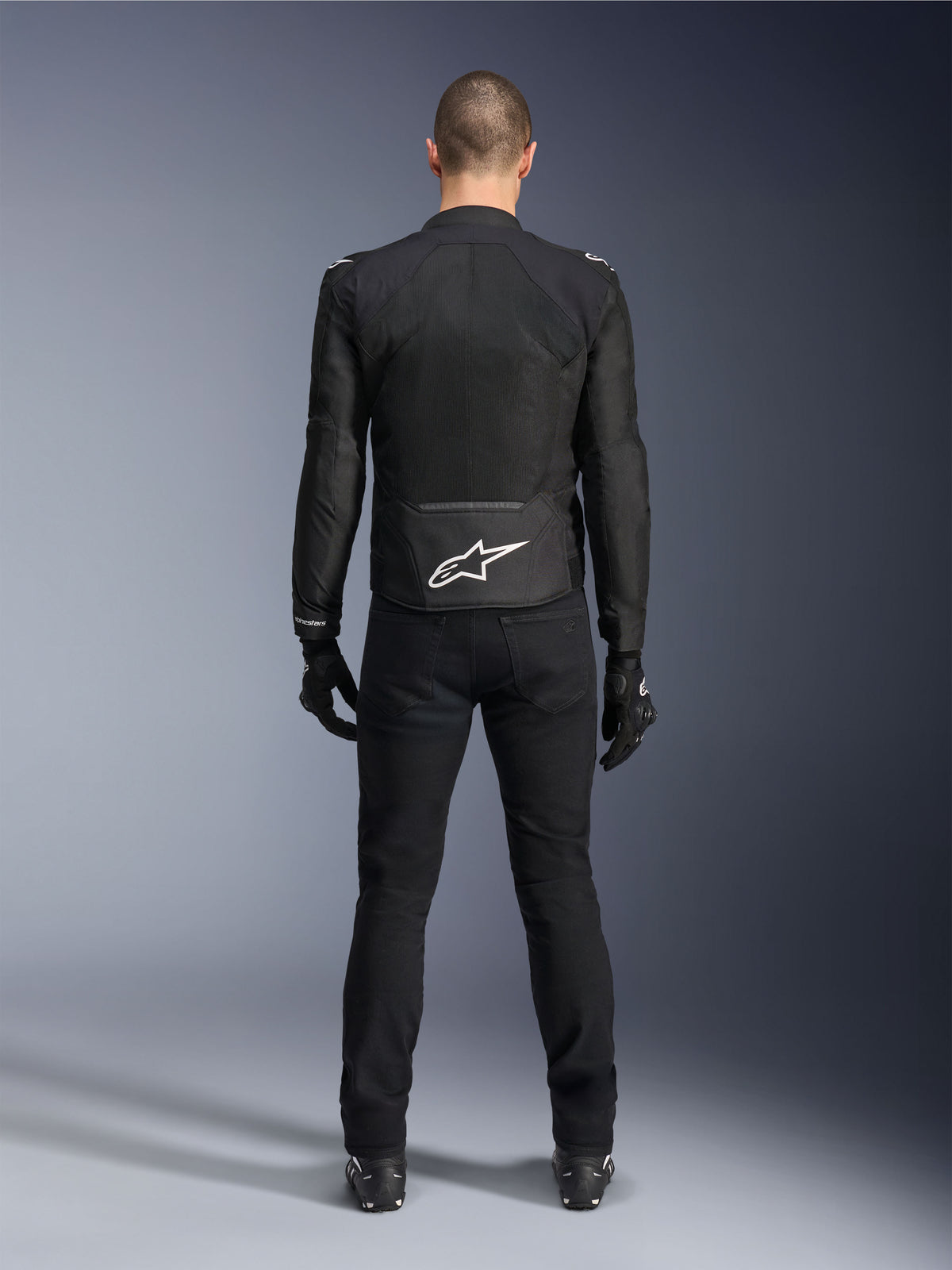 Veste Alpinestars Viper Air V4, veste de moto en textile noir, vue de dos avec logo étoile Alpinestars blanc sur le bas du dos, portée avec un pantalon de moto et des gants noirs, équipement d'été pour la conduite sur route et sportive