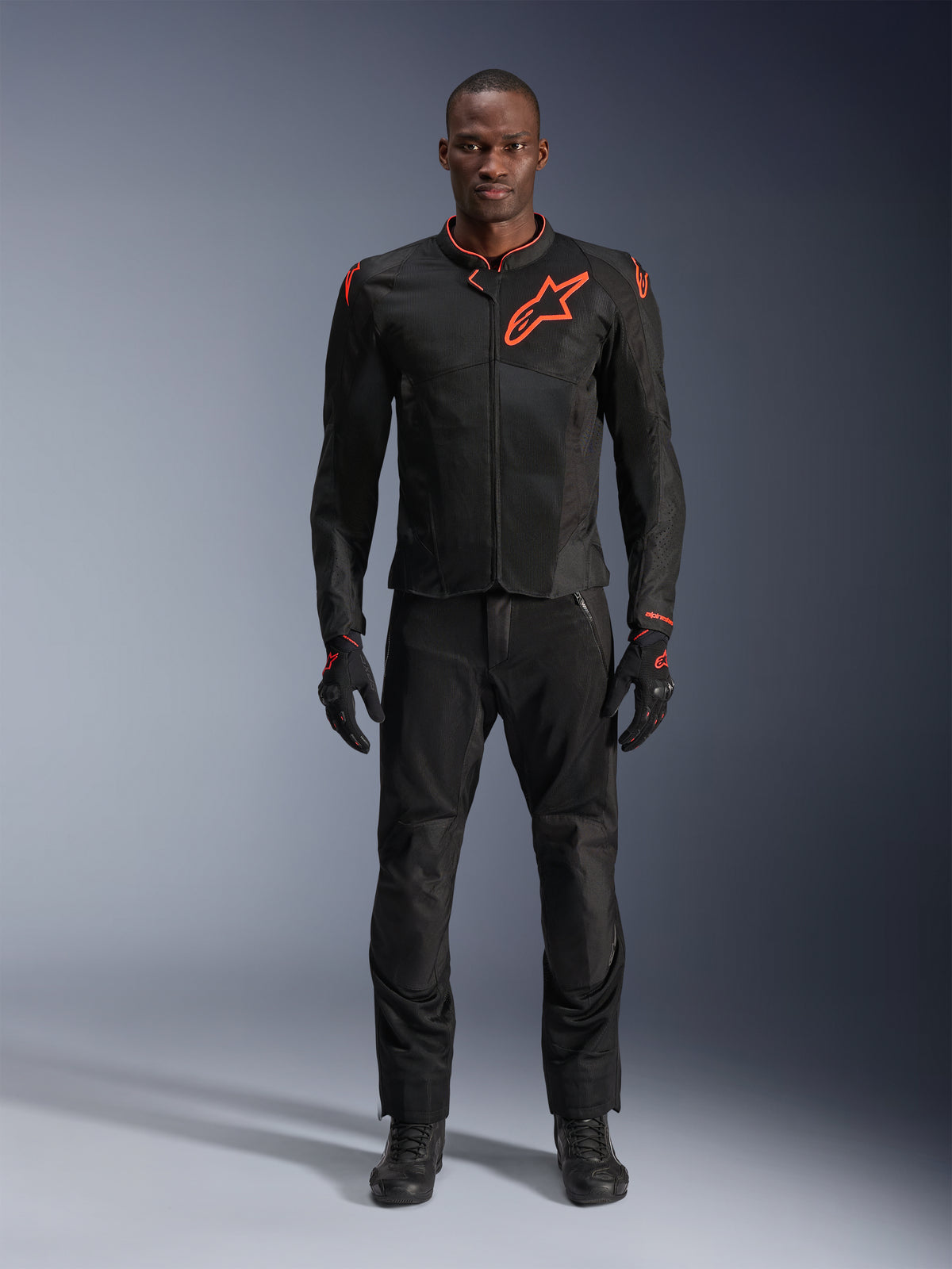 Veste Alpinestars Viper Air V4 en Noir et Rouge Fluo, portée par un mannequin avec pantalon et gants noirs assortis, présentant des panneaux en mesh pour la circulation de l'air et un logo Alpinestars rouge sur la poitrine, équipement de route sportif pour moto