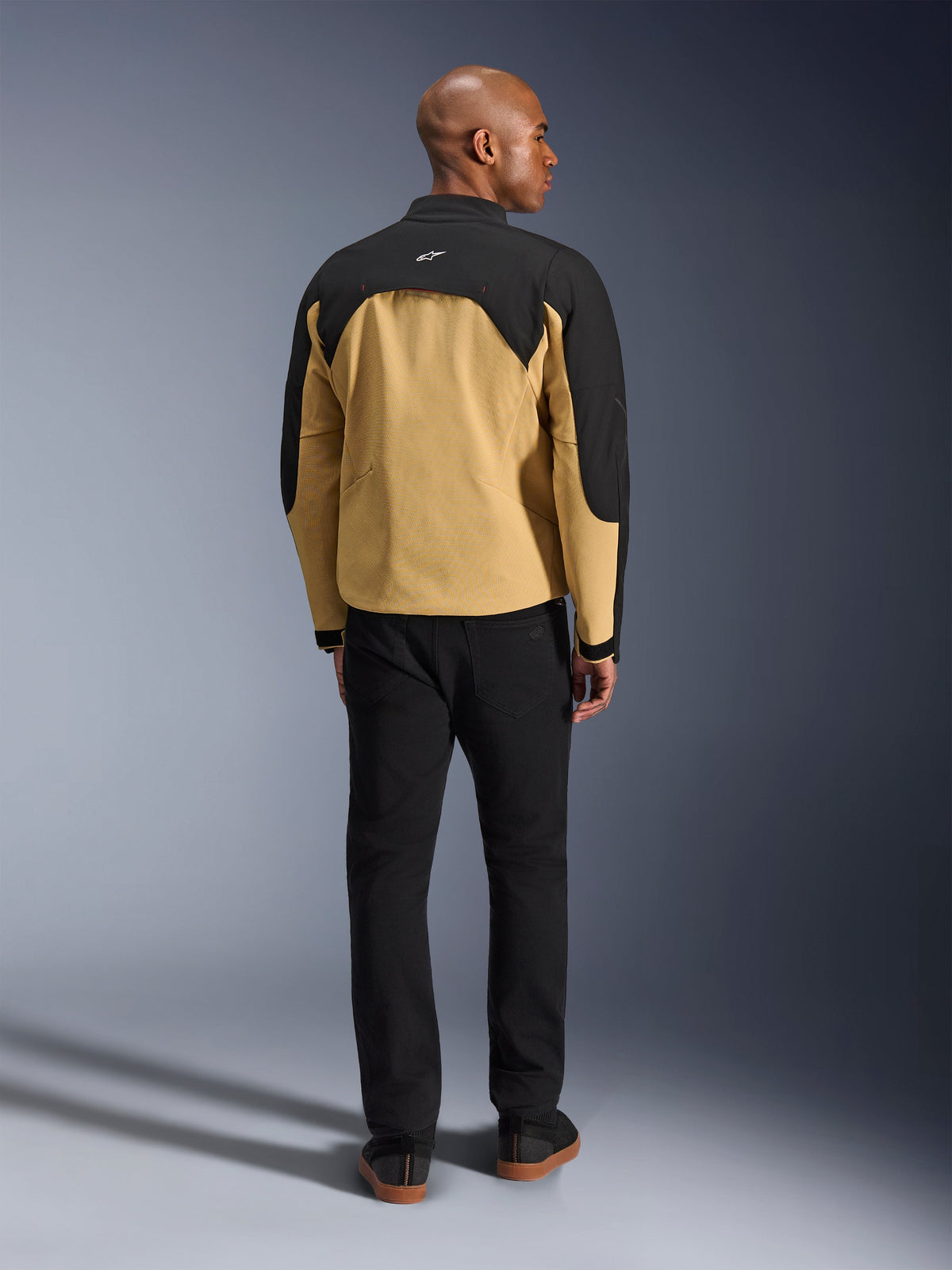 Veste Alpinestars Provoke, Noir et Camel, vue arrière d'une veste de moto urbaine présentant un empiècement supérieur noir et un bas du dos camel, portée par un mannequin avec un pantalon noir, design contemporain d'inspiration streetwear