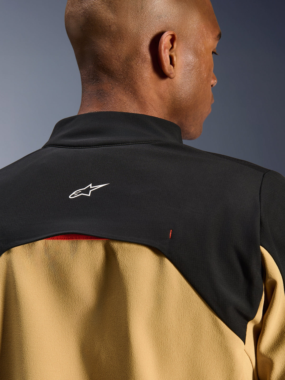 Veste Alpinestars Provoke, veste de moto urbaine, noir et camel, gros plan sur le haut du dos et le col présentant un logo Astars blanc sur un empiècement noir avec des panneaux inférieurs camel, design technique contemporain d'inspiration outdoor