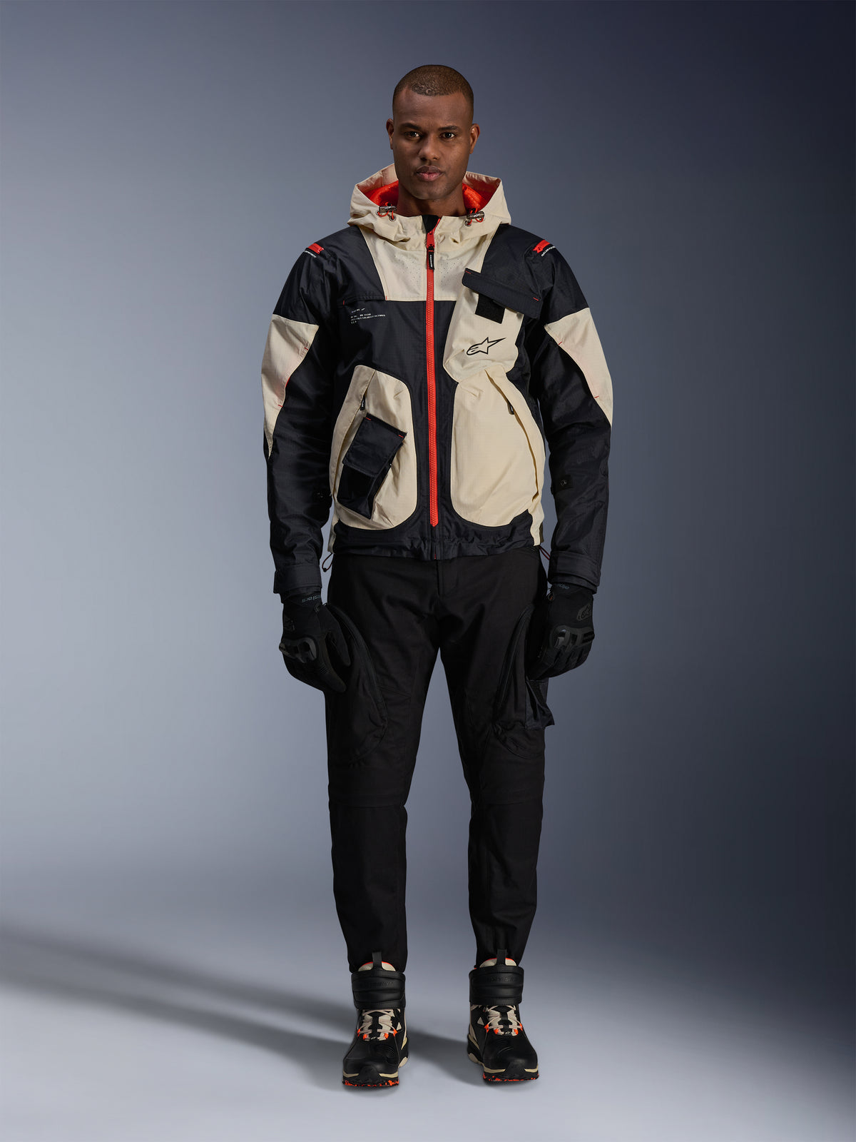 Alpinestars Mogress Air, veste de moto urbaine pour homme, noire et amande avec détails orange vif, portée par un mannequin.