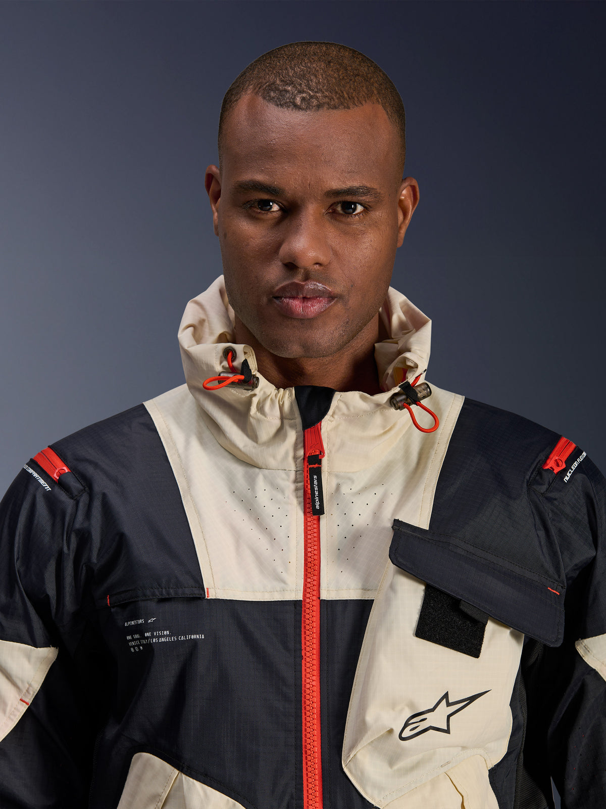 Alpinestars Mogress Air, veste de moto urbaine pour homme, noire et orange vif, textile ripstop avec capuche et design color-block.