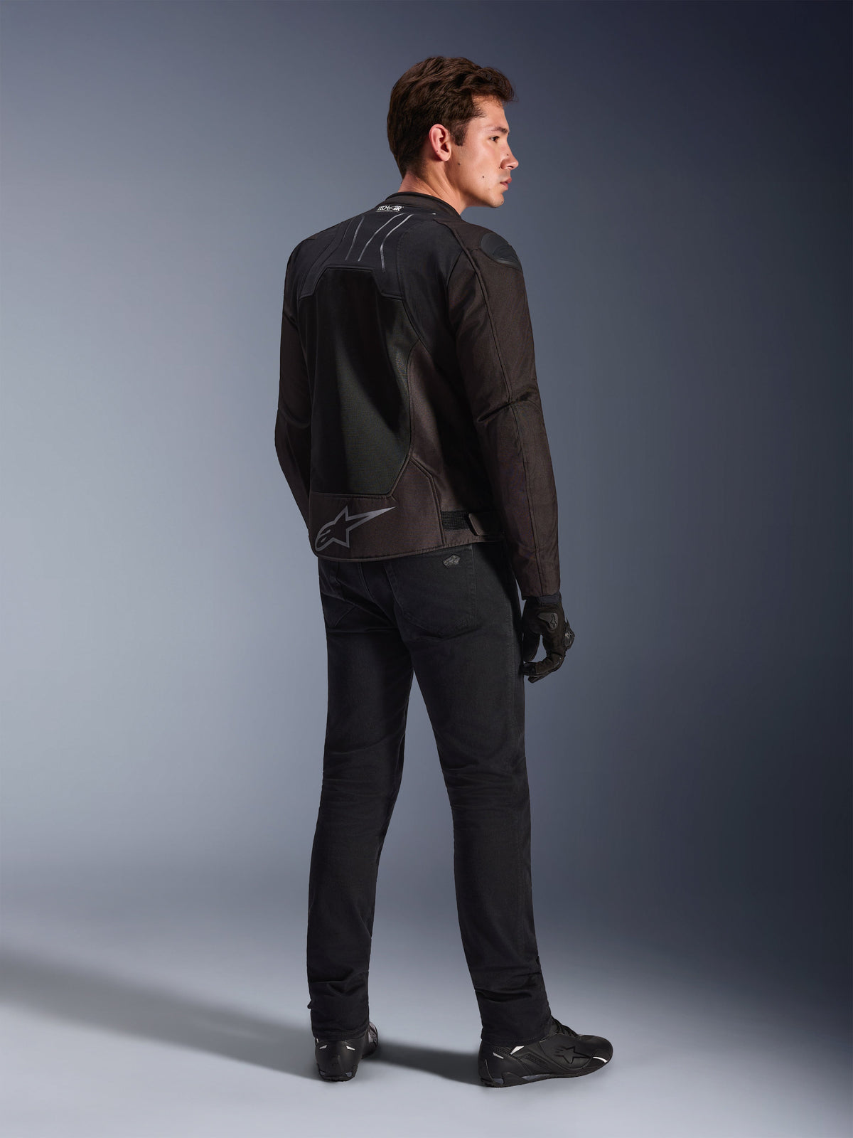 Veste Alpinestars SMX Air en Black Anthracite, vue de dos sur modèle, avec marquage Tech-Air® Ready sur le col et logo Astar au bas du dos, portée avec pantalon et chaussures de moto noirs