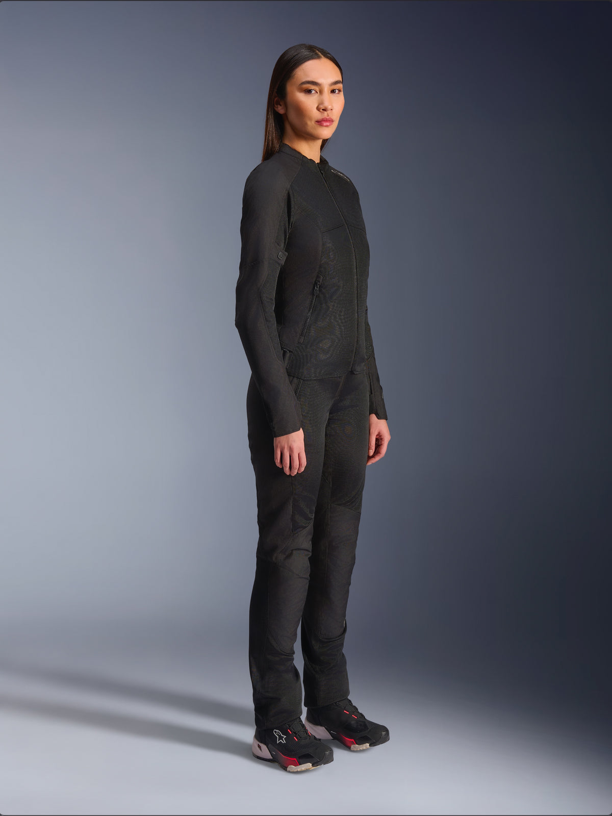 Veste Alpinestars Stella C-1 Air pour femme en noir, veste de moto en textile avec empiècements en mesh, portée avec un pantalon de moto noir assorti et des baskets techniques, photo de studio présentant une tenue de route urbaine complète.