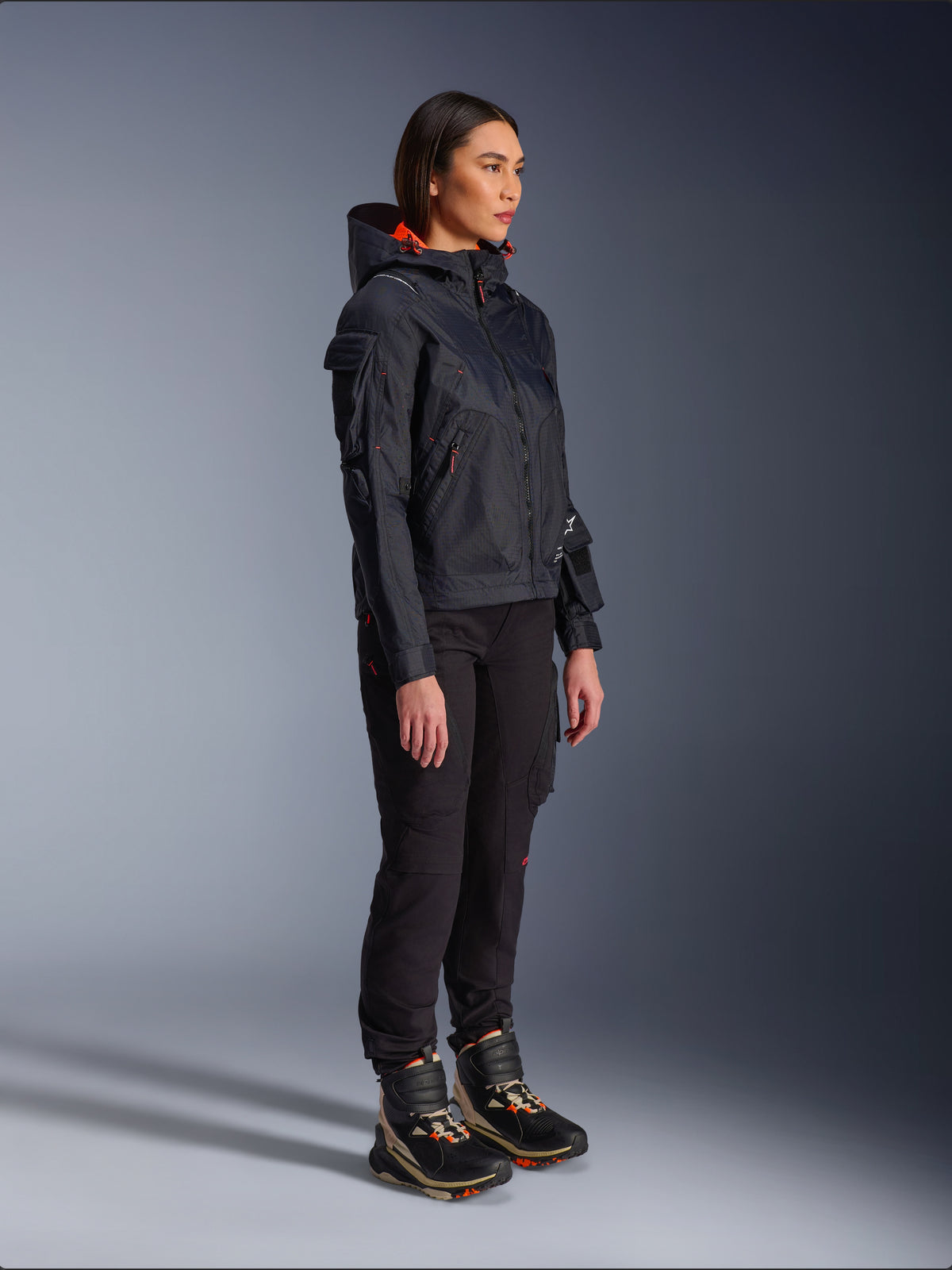Pantalon femme Alpinestars Actea noir, coupe régulière avec poches cargo, associé à une veste Molly Air noire aux accents orange et des chaussures de moto montantes, vêtements de moto urbains contemporains pour femmes