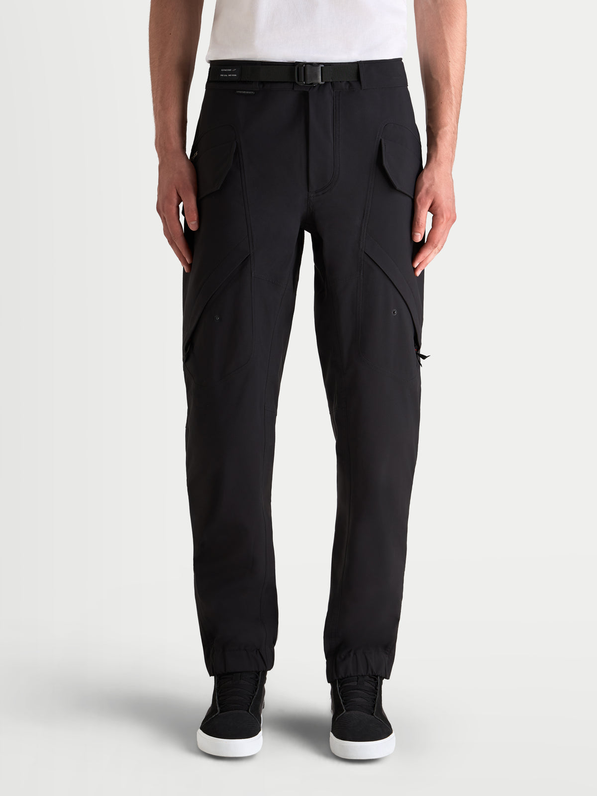 Alpinestars Juggernaut V2 Drystar® Pants, men's urban contemporary motorcycle pants in black, front view on a model showing utility cargo pockets, laminated waterproof textile construction, and adjustable belt.