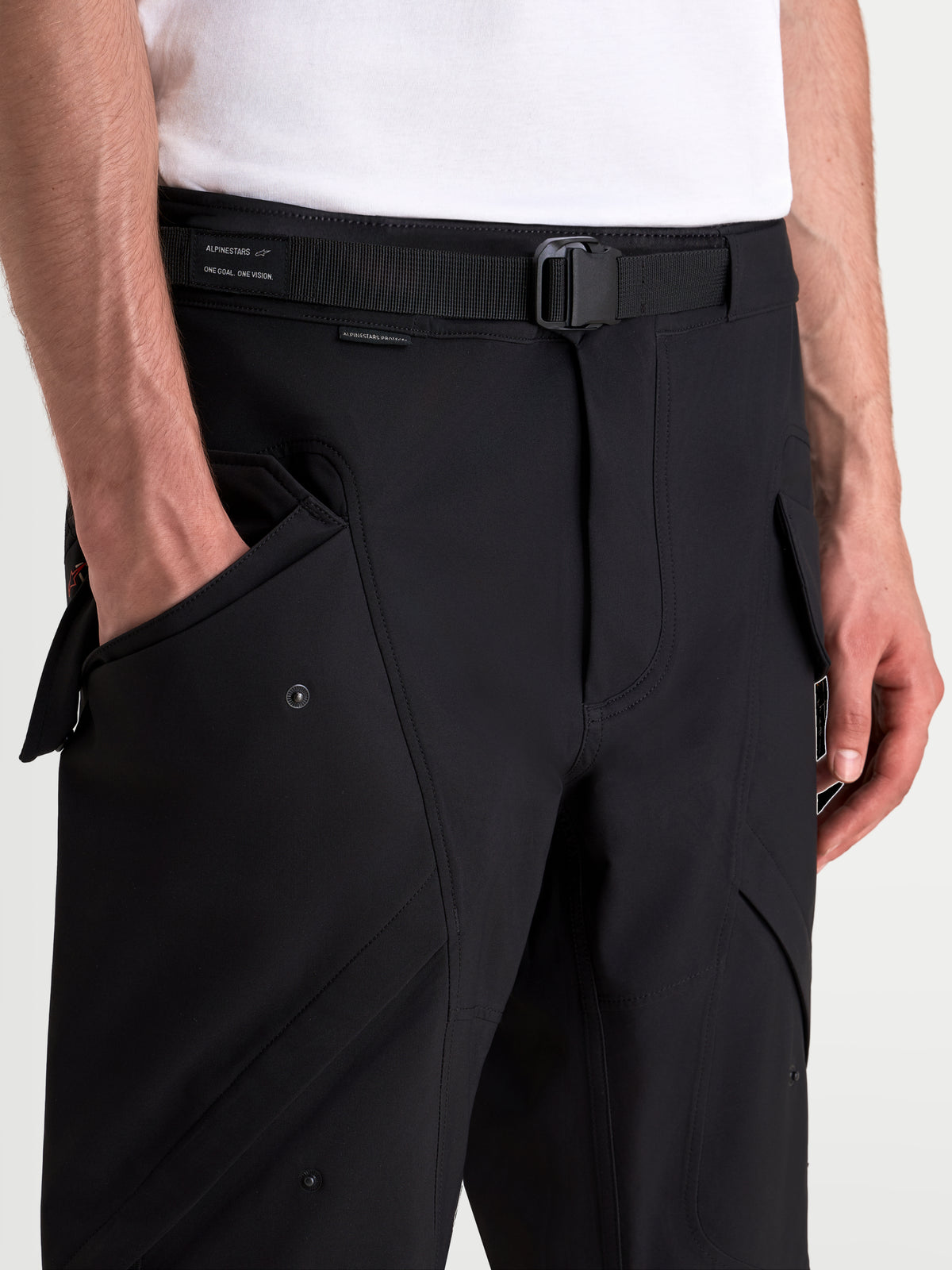 Alpinestars Juggernaut V2 Drystar Pants, men's waterproof urban motorcycle pants in black, close-up view showing the adjustable belt, magnetic buckle, and side cargo pockets on a model
