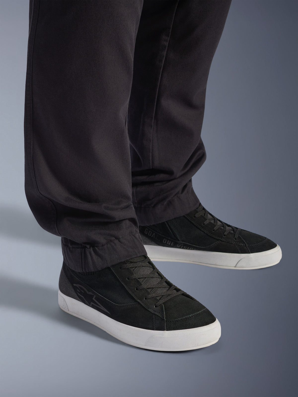 Pantalon Cargo Flex-AST Court Alpinestars, pantalon de moto urbain, noir, avec jambes fuselées et ourlets élastiqués, associé à des baskets Alpinestars noires, style de conduite urbain contemporain
