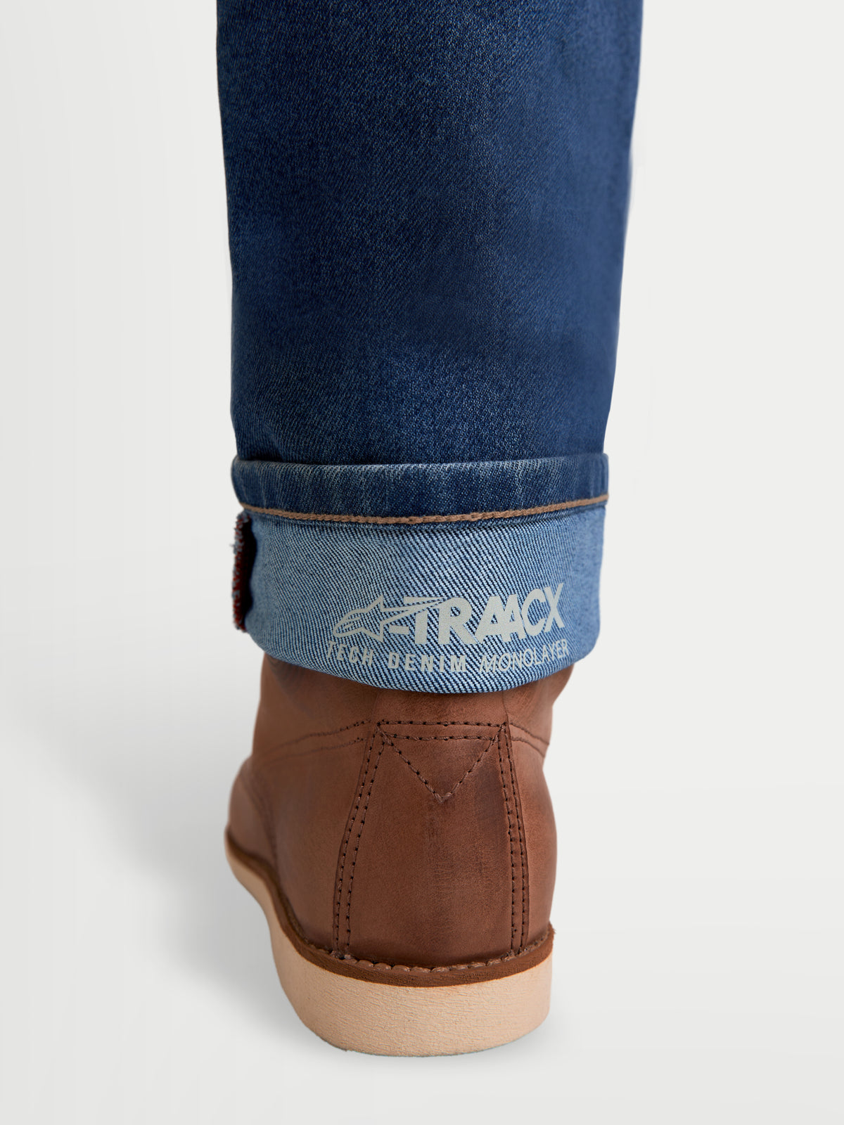 Alpinestars Flex Ast 7 Denim Pantalons, pantalon de moto urbain pour homme, bleu clair, vue détaillée du bas de jambe retroussé affichant le marquage denim monolayer A-TRAACX et des bottes de moto marron
