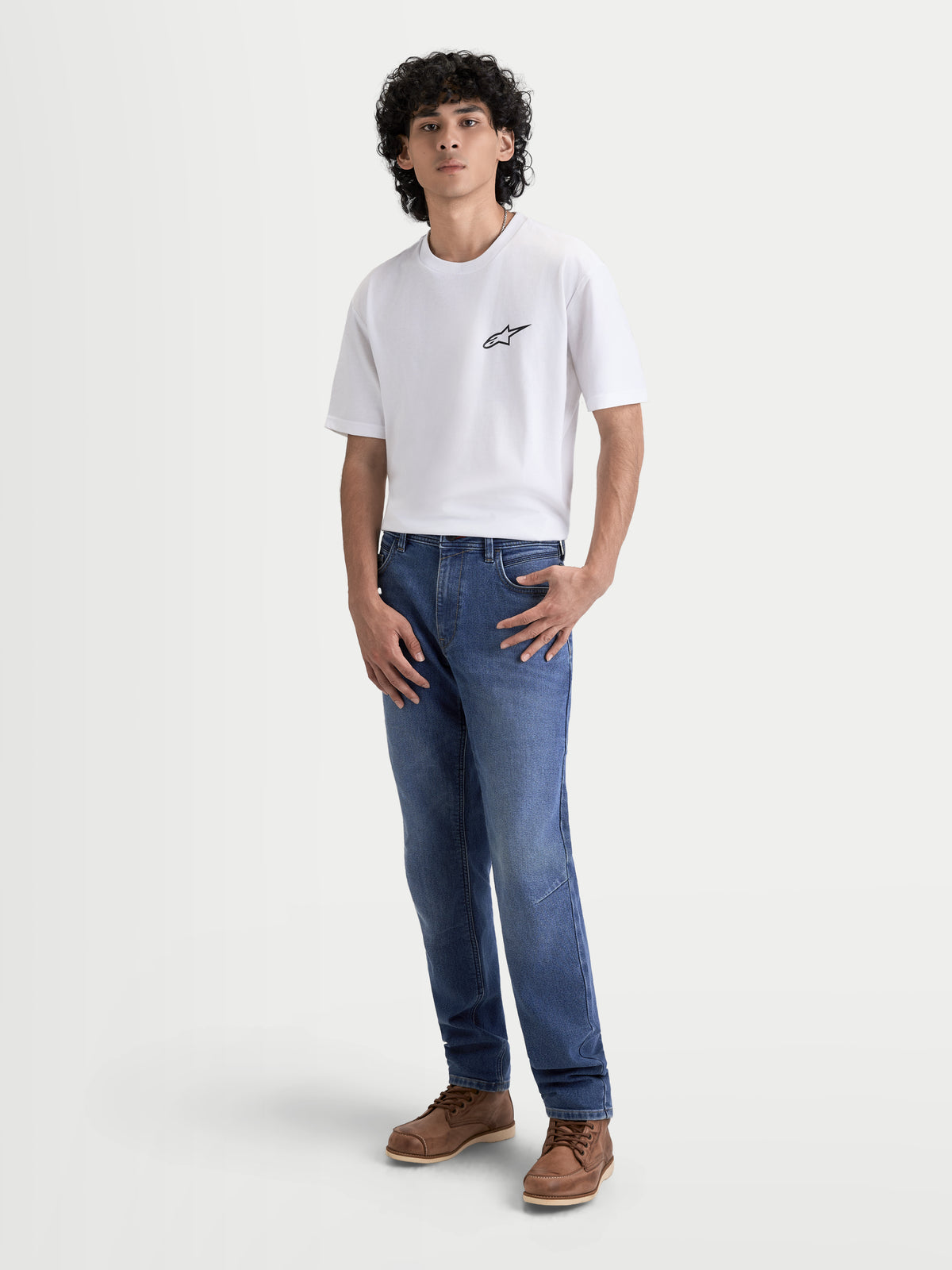 Alpinestars Flex-AST 7 Denim Pantalons, pantalon de moto urbain pour homme en bleu clair, vue de face sur un modèle portant un t-shirt blanc et des bottes marron