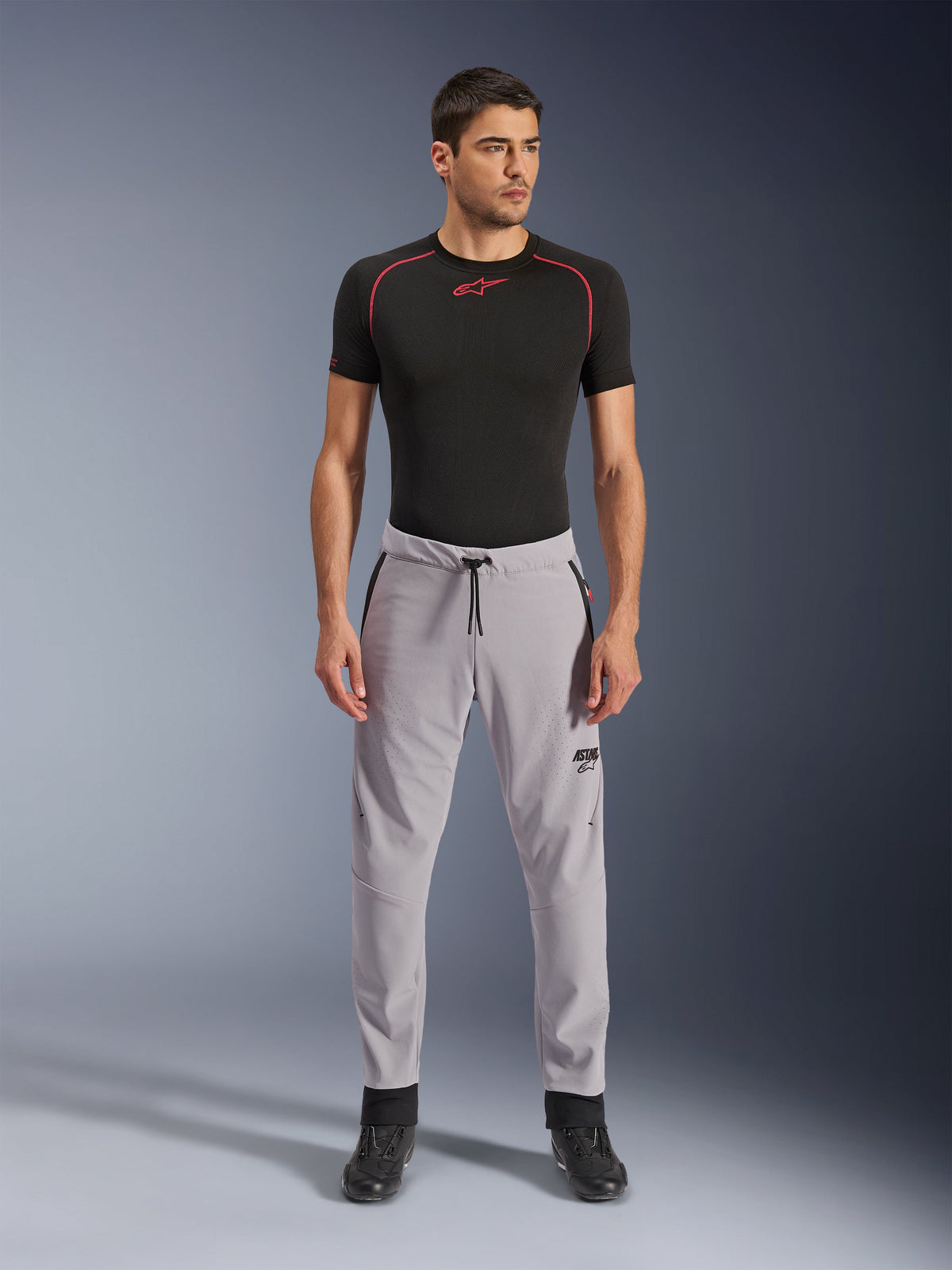 Alpinestars Aeroshell Airflow Pants, Mid Gray, lightweight textile pants featuring laser-perforated ventilation zones and a drawstring waist, worn by a model with a black compression shirt and black motorcycle boots, clean and modern sport riding design