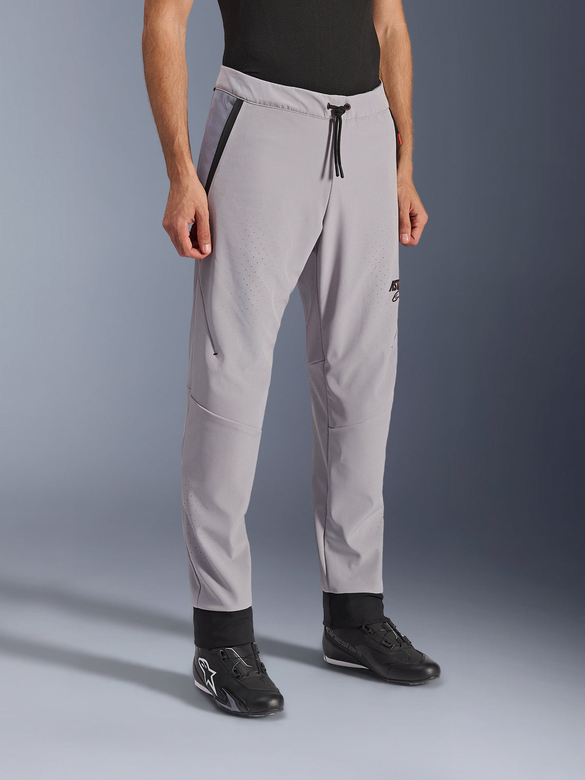 Alpinestars Aeroshell Airflow Pants, Mid Gray, lightweight motorcycle pants with laser-perforated ventilation zones on the thighs and shins, featuring a drawstring elastic waistband and a slim sport fit, styled on a model wearing black riding shoes.