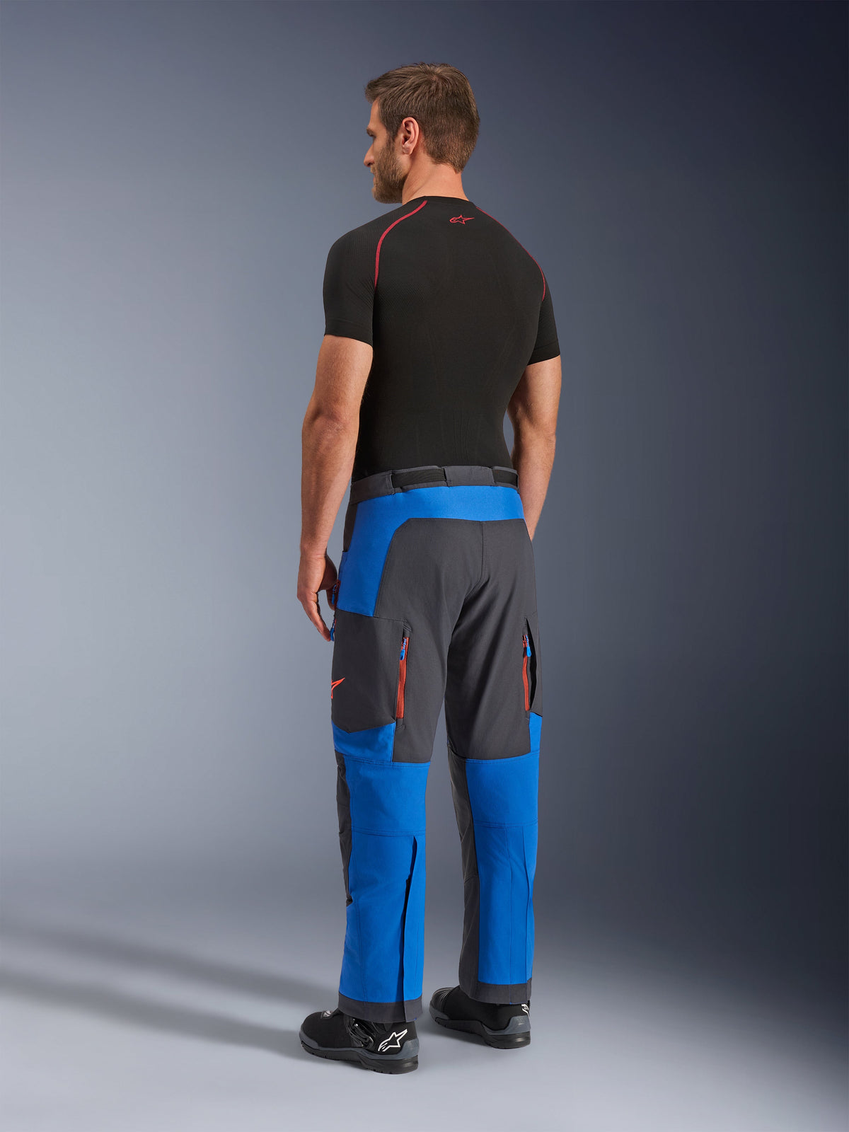 Alpinestars Maxdura Dual Pants, Adventure Motorcycle Pants, Royal Blue and Deep Gray, back-side view worn by a model, featuring orange zippered vents, over-the-boot adventure fit, and durable stretch material.