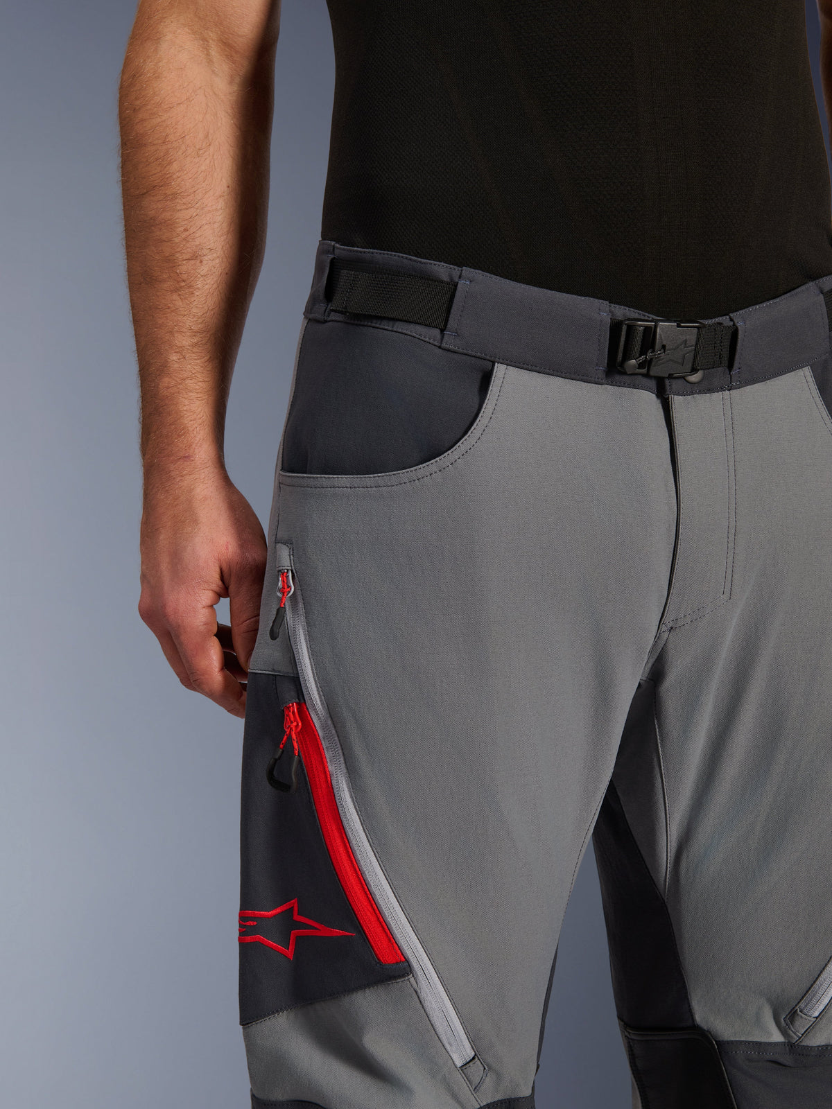 Alpinestars Maxdura Dual Pants, pantalon de moto d'aventure, gris foncé et gris profond, gros plan avec ceinture réglable à boucle magnétique, poche cargo zippée avec détails rouges et logo Alpinestars.