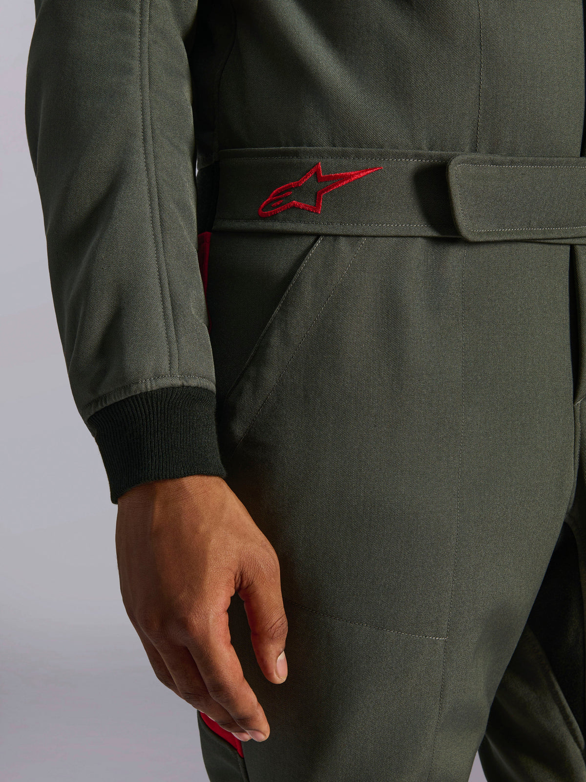 Alpinestars GP Race V3 Suit FIA, Auto Racing Suit, Anthracite Red, close-up of the adjustable waist belt featuring a red embroidered logo and black ribbed sleeve cuff on textured twill fabric