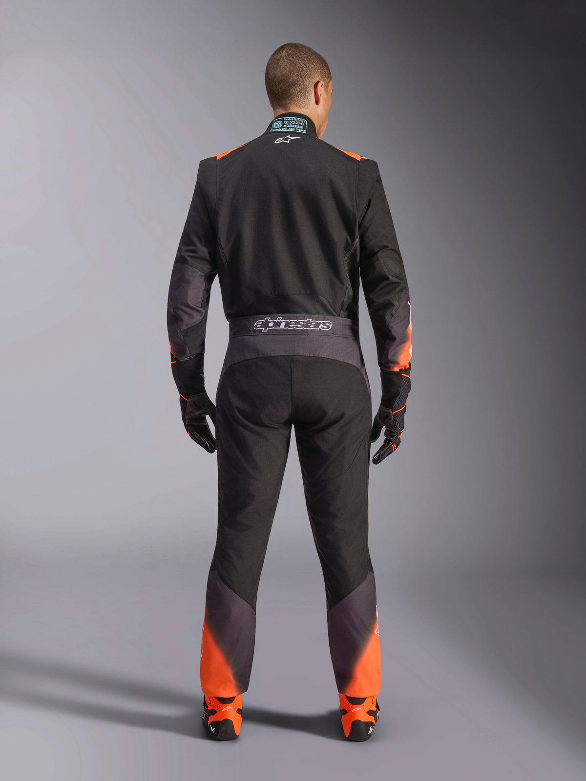 Alpinestars KMX-5 V3, combinaison de karting pour homme, noire et orange fluo, certifiée FIA, vue arrière avec marquage.