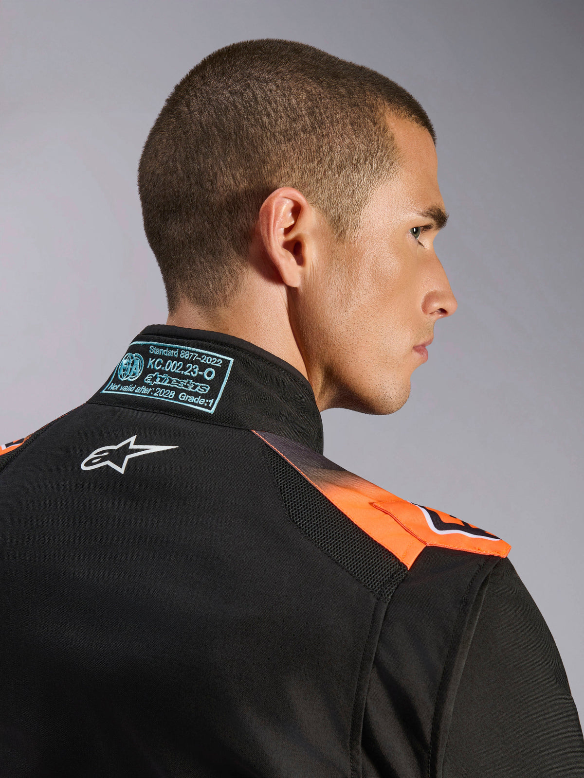 Alpinestars KMX-5 V3, combinaison de karting noire et orange fluo, certifiée FIA 8877-2022, détail du col en mesh.