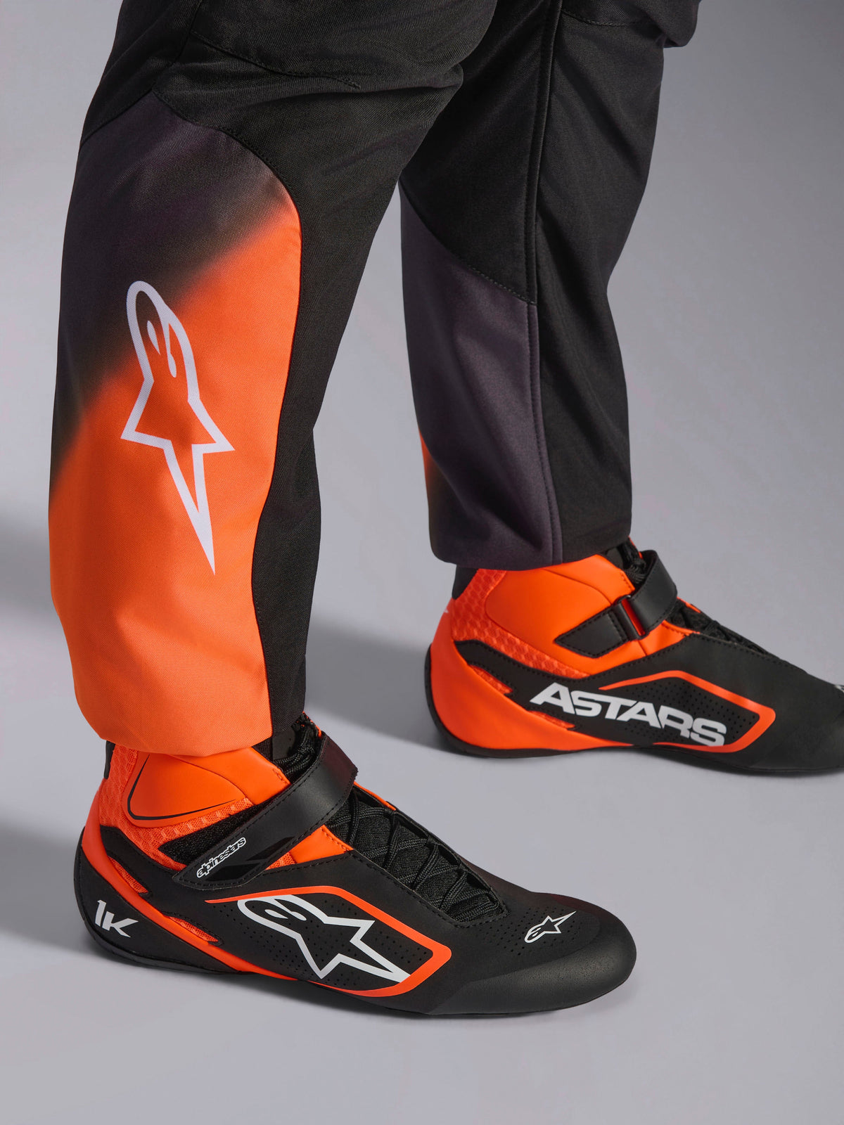 Alpinestars KMX-5 V3, combinaison de karting pour homme, noire et orange fluo, certifiée FIA, gros plan sur les jambes.