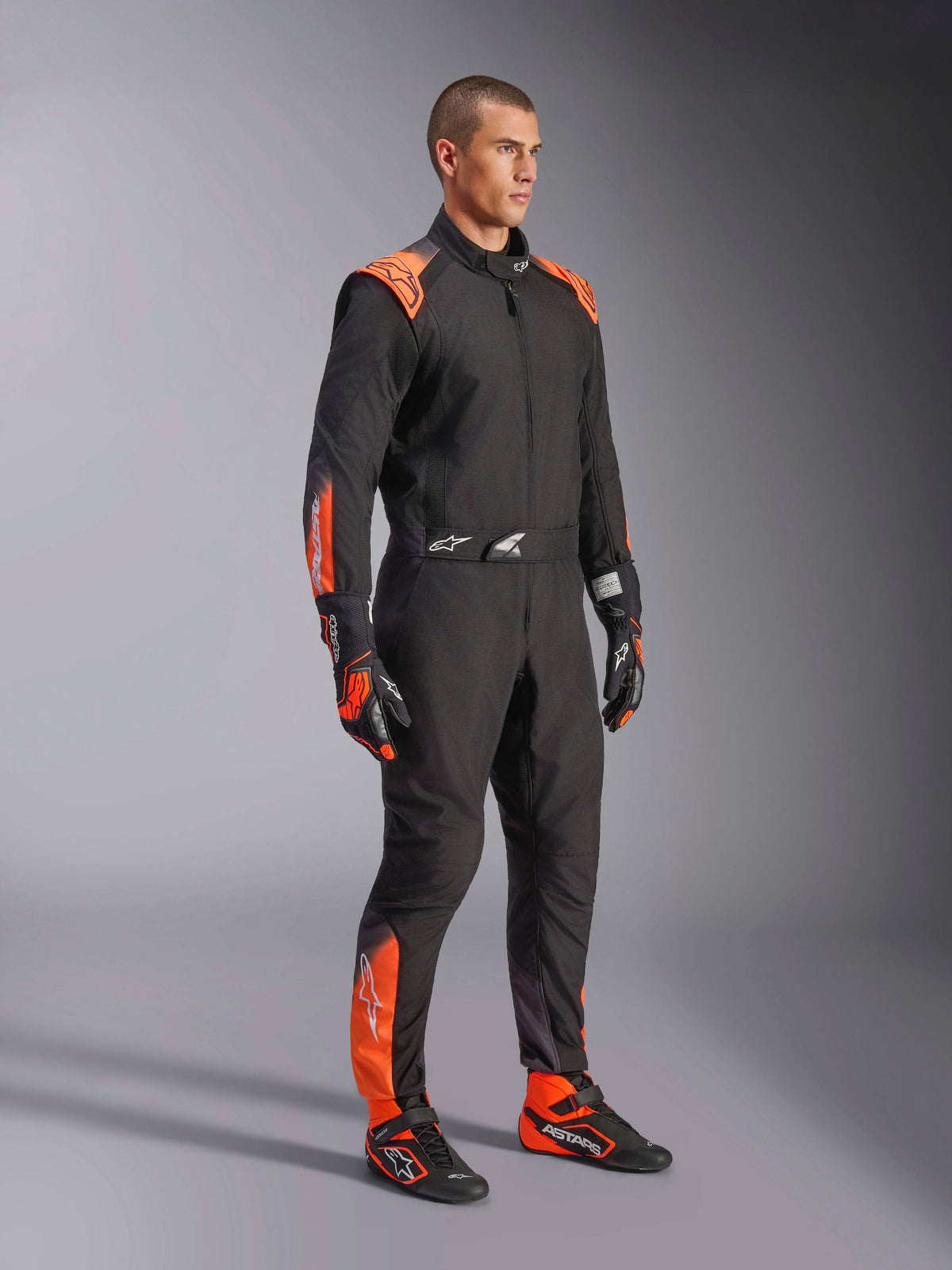 Combinaison Alpinestars KMX-5 V3 de karting homme, noire et orange fluo, homologuée FIA grade 1, sur mannequin.