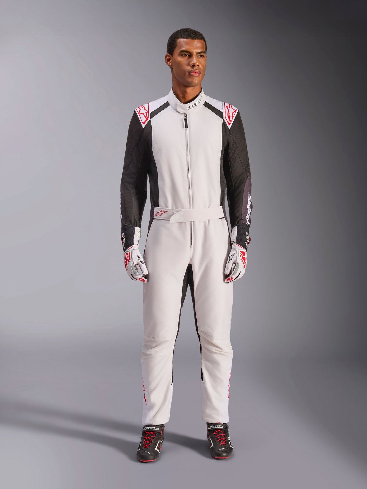 Combinaison Alpinestars KMX-5 V3, combinaison de karting une pièce, blanc, noir et rouge vif, portée par un mannequin avec des gants et des chaussures de course assortis, équipement professionnel de sport automobile pour le karting de compétition.