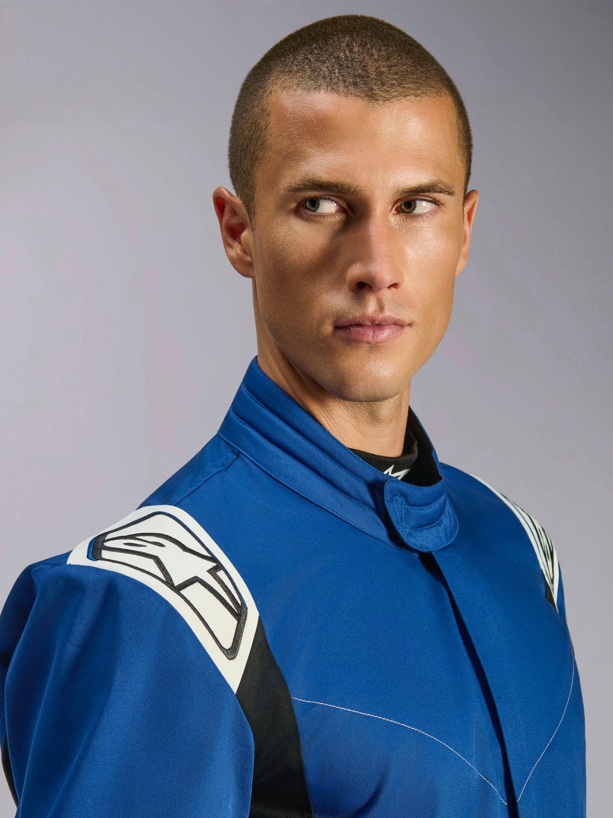 Combinaison Alpinestars Kart Indoor V2, combinaison de karting bleue, vue rapprochée d'un mannequin, empiècements d'épaule blancs avec logo étoile noir, col ergonomique, sergé monocouche durable pour le karting de loisir.