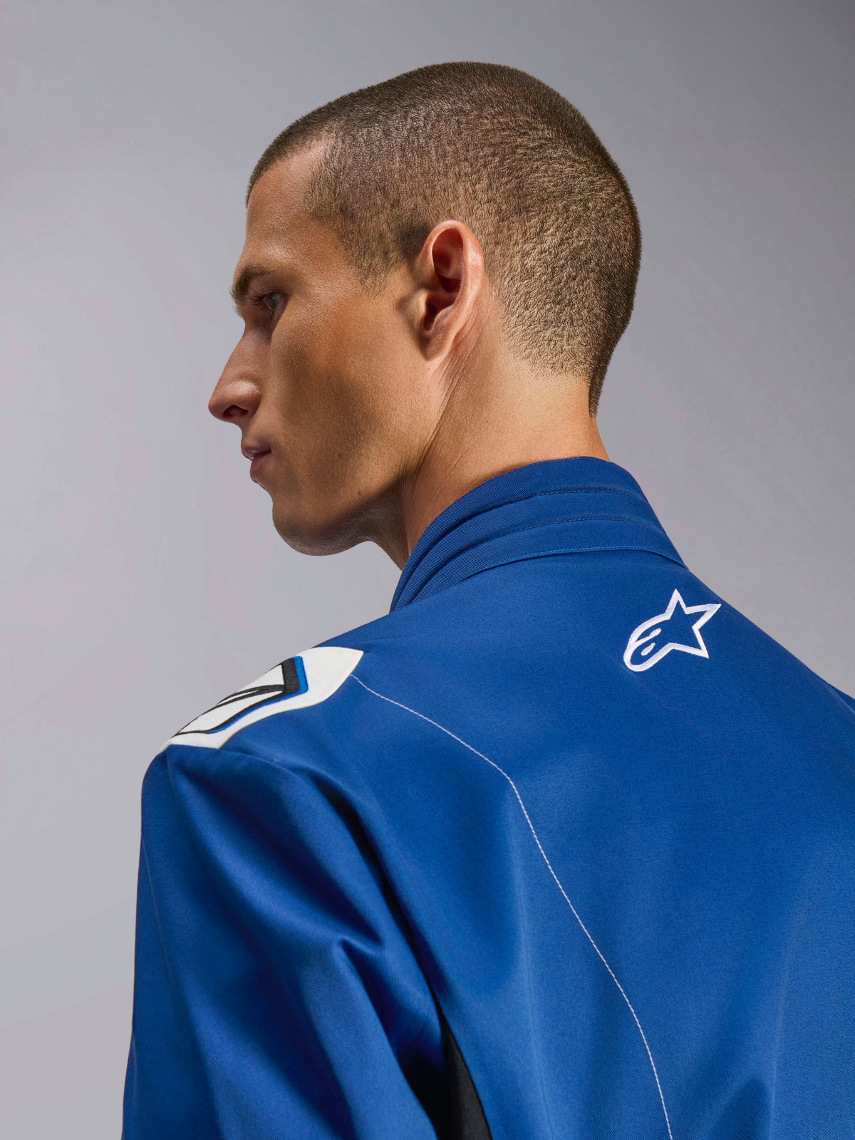 Combinaison Alpinestars Kart Indoor V2, combinaison de karting bleue, gros plan de profil du col ergonomique et du haut du dos avec logo étoile blanc, présentant un design d'épaule inspiré de la Formule 1 et une construction durable en sergé poly-coton