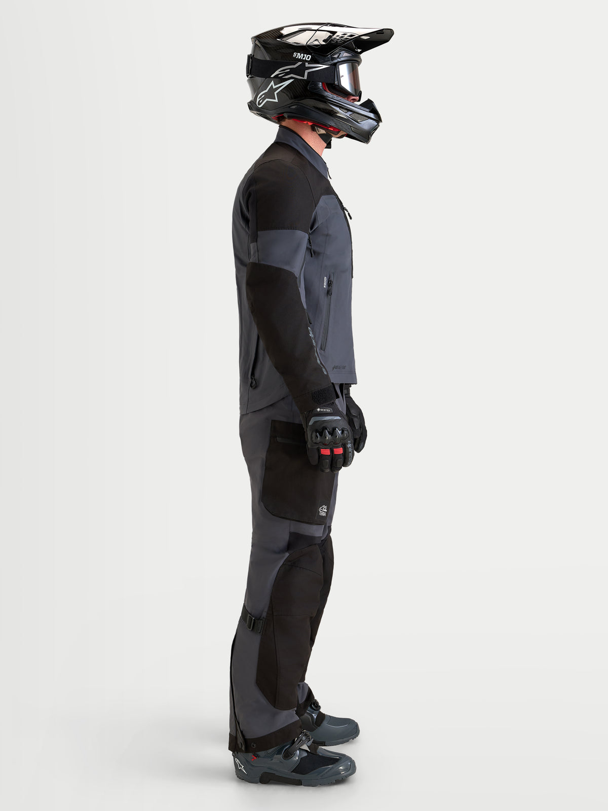 Alpinestars Arenis Gore-Tex Tenue complète, ensemble de moto adventure imperméable pour homme en noir et gris foncé, vue de profil sur un modèle portant un casque et des bottes assortis
