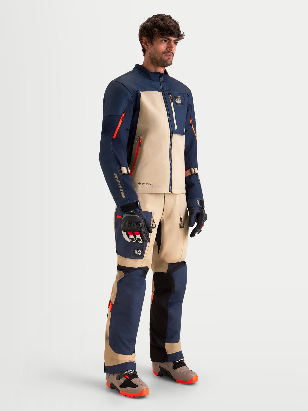 Alpinestars Tenue complète Arenis Gore-Tex, veste et pantalon de moto adventure pour homme en bleu nuit et aluminium, vue de studio de plain-pied sur un modèle portant un équipement de protection et des bottes assortis