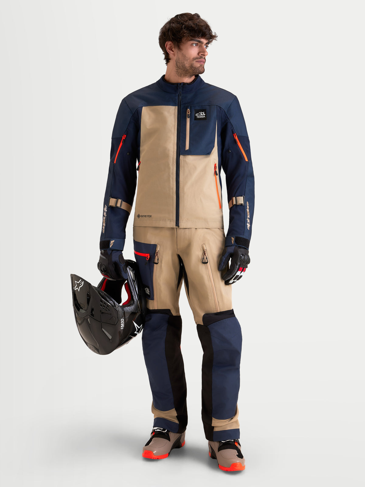 Alpinestars Arenis Gore-Tex Gear Set, tenue complète de moto adventure pour homme en bleu marine, indigo et aluminium, vue de face complète sur un modèle portant l'équipement assorti et tenant un casque, vêtement de conduite étanche certifié AA