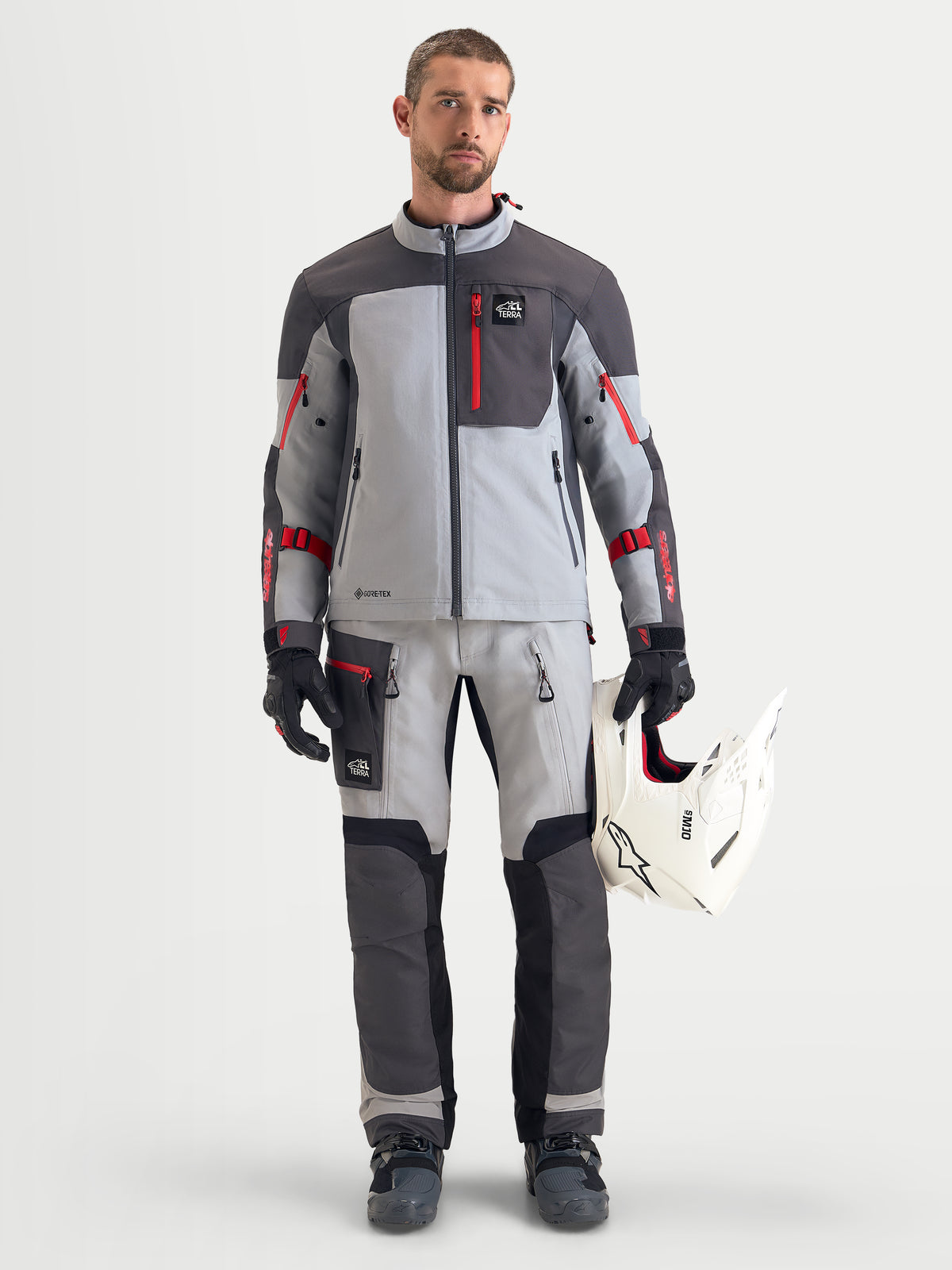 Alpinestars Arenis Gore-Tex Veste, veste de moto adventure pour homme en gris moyen, gris foncé et noir, portée par un modèle tenant un casque blanc