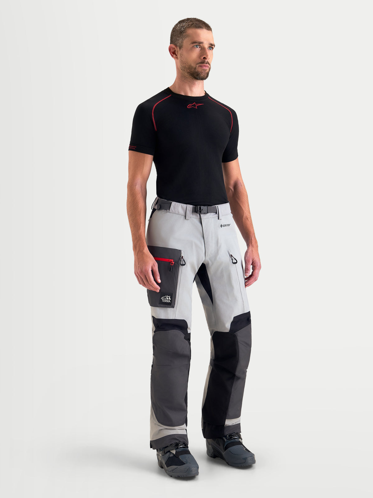 Alpinestars Arenis Gore-Tex Pantalons, pantalon de moto adventure pour homme gris clair, gris foncé et noir, vue de face sur un modèle portant un équipement textile imperméable avec poches cargo