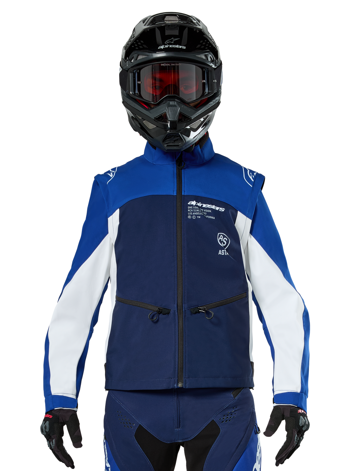 Pilote de motocross portant la veste Softshell Alpinestars Lite-Dura en Navy Bright Blue White, vue de face, associée à un casque noir et des lunettes teintées rouges, conception technique coupe-vent avec poches zippées et accents blancs pour l'enduro tout-terrain
