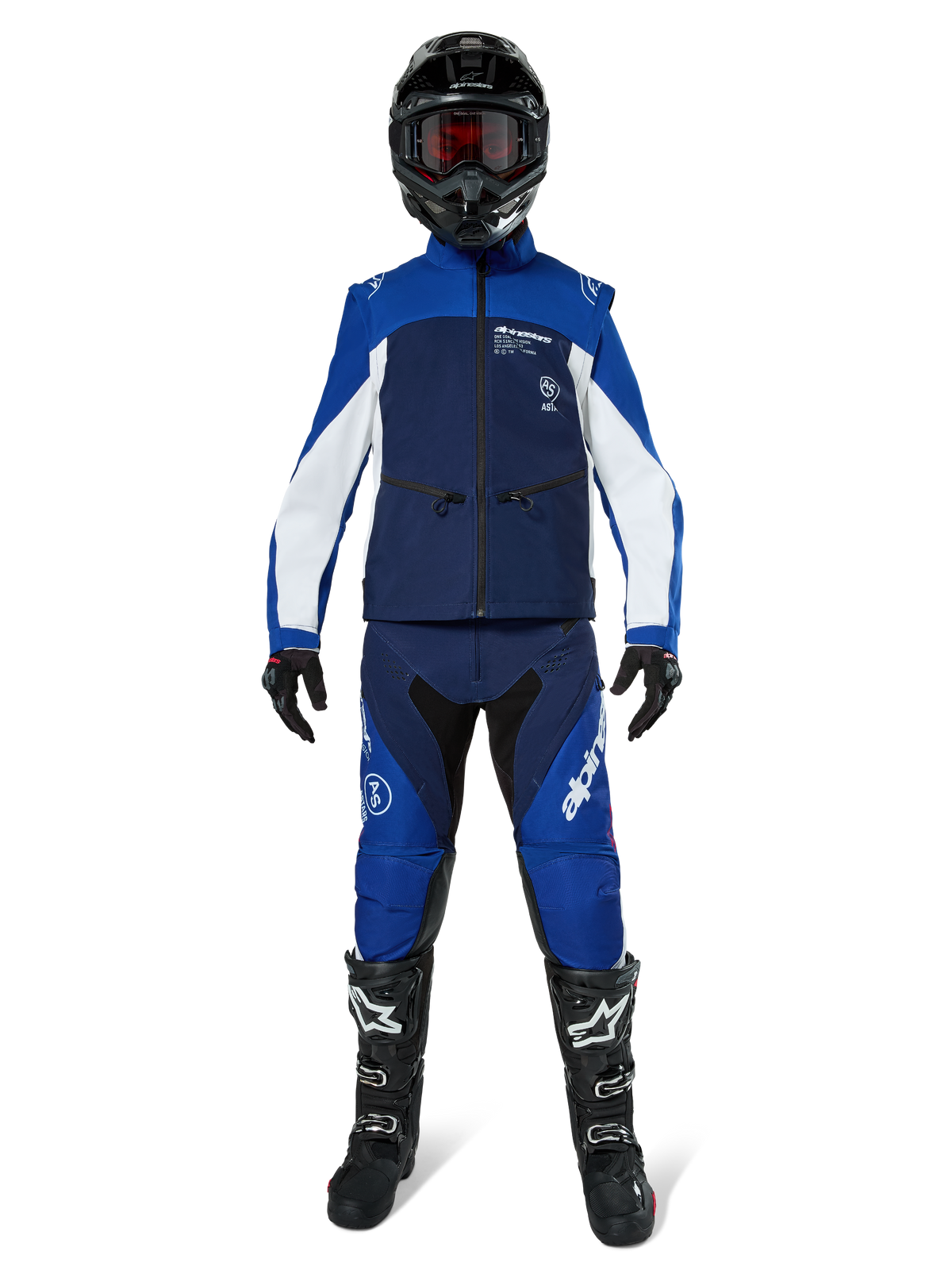 Veste Softshell Alpinestars Lite-Dura, veste de moto tout-terrain bleu marine, bleu vif et blanc, portée avec une tenue complète assortie comprenant un casque noir, un pantalon d'enduro et des bottes noires, vêtement technique coupe-vent pour la pratique du tout-terrain