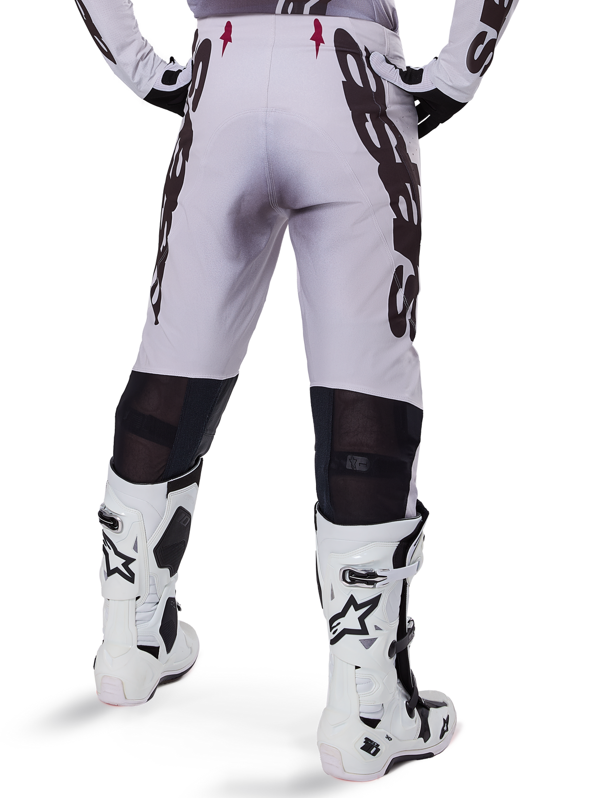 Pantalon Alpinestars Supertech Maker 2025, pantalon de motocross, argent et noir, vue arrière montrant de grands logos noirs sur les cuisses et des zones en mesh respirant derrière les genoux, porté avec des bottes Alpinestars blanches