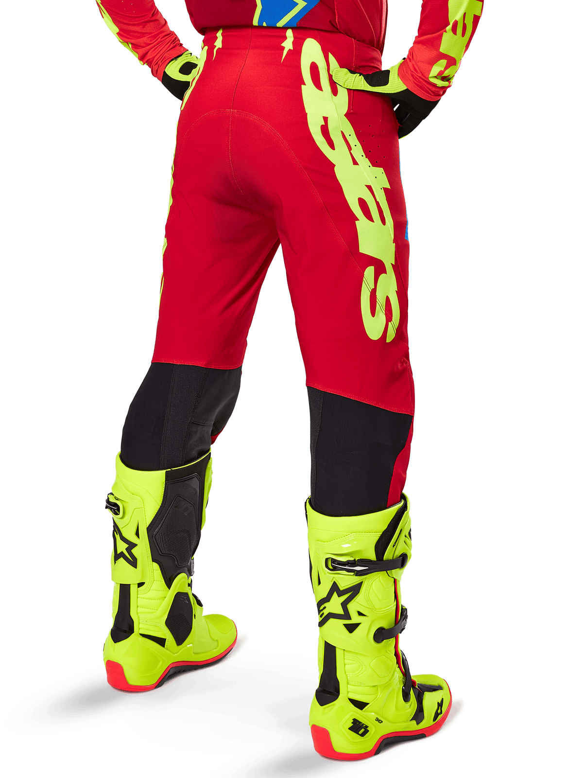 Alpinestars Supertech Maker Pants 2025, pantalon de motocross, rouge vif et jaune fluo, vue arrière, avec marquage jaune audacieux, panneaux noirs derrière les genoux, porté avec des bottes jaune fluo assorties, conçu pour des performances tout-terrain de niveau professionnel