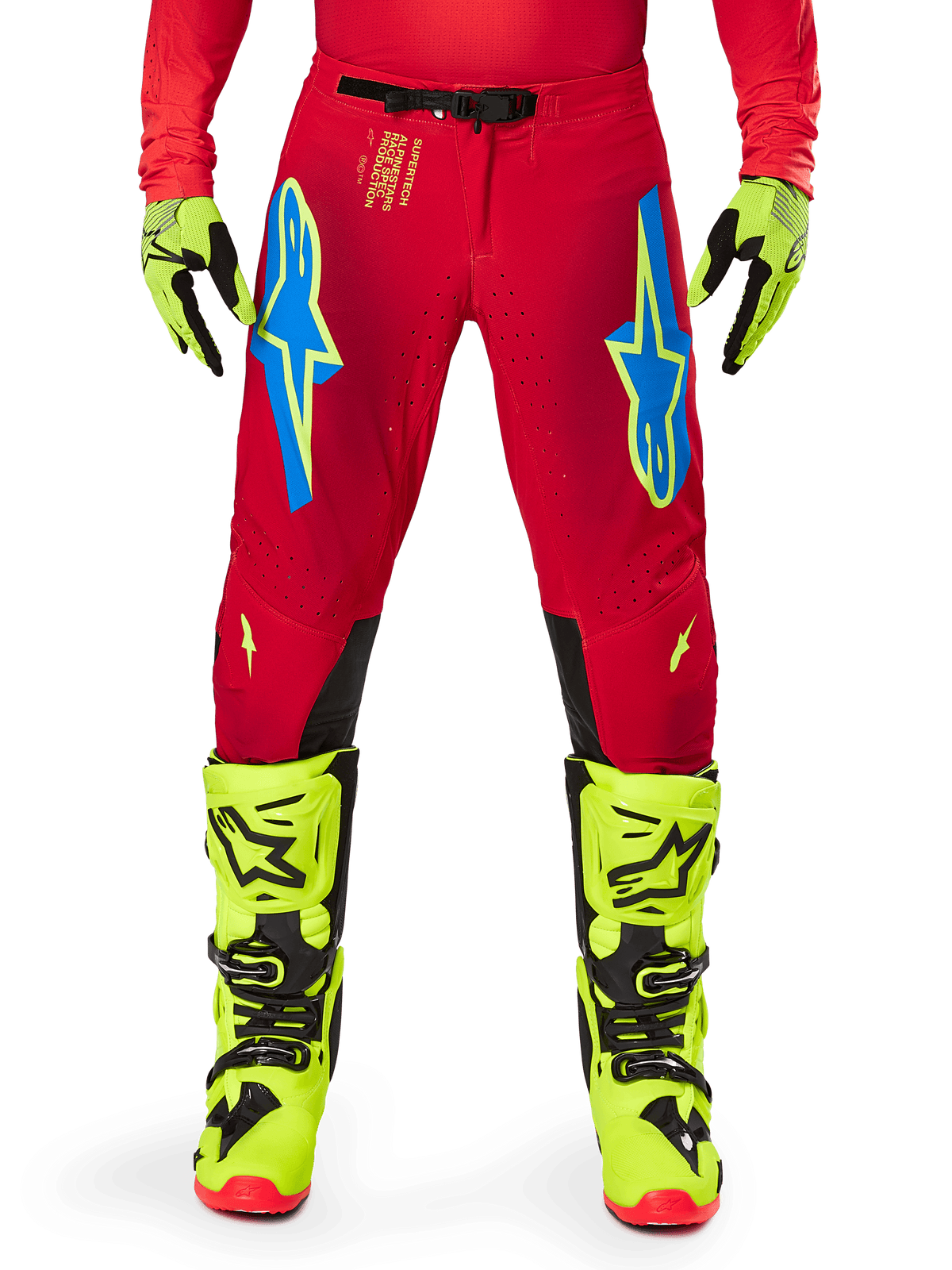 Pantalon Alpinestars Supertech Maker 2025, pantalon de motocross, rouge vif et jaune fluo, avec logos Astars bleus sur les cuisses, perforations de ventilation et panneaux intérieurs noirs aux genoux, porté avec des bottes et des gants jaune fluo assortis
