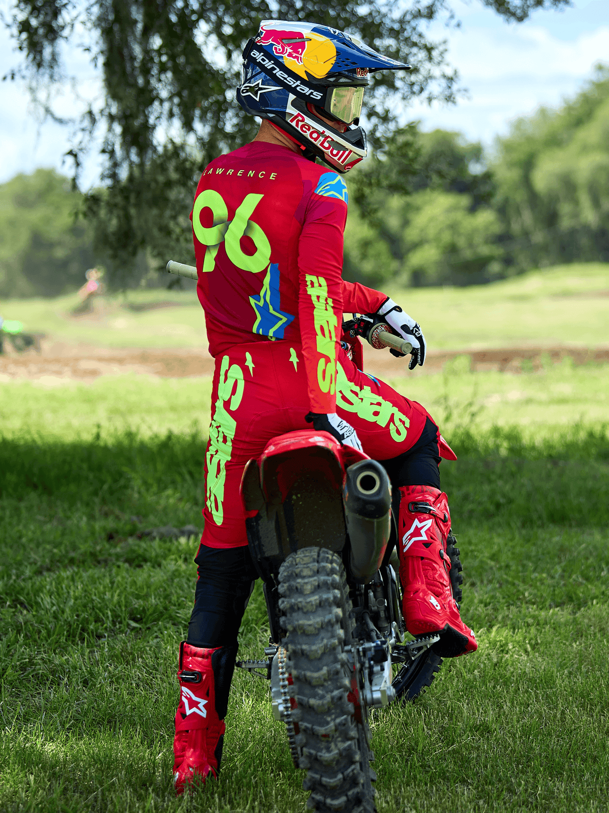 Pilote de motocross portant la tenue Alpinestars Supertech Maker 2025 en rouge vif et jaune fluo, assis sur une moto rouge, numéro 96 sur le maillot, bottes et casque rouges assortis, équipement de course professionnel pour performance tout-terrain