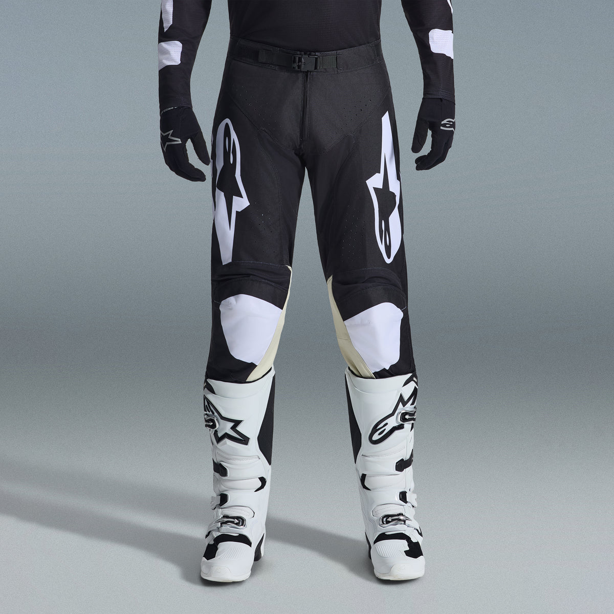 Ensemble d'équipement Alpinestars Racer Air Riway 2026, pantalon de motocross noir et blanc avec panneaux intérieurs aux genoux beiges, associé à des bottes de course blanches et des gants noirs, équipement de course tout-terrain léger et ventilé