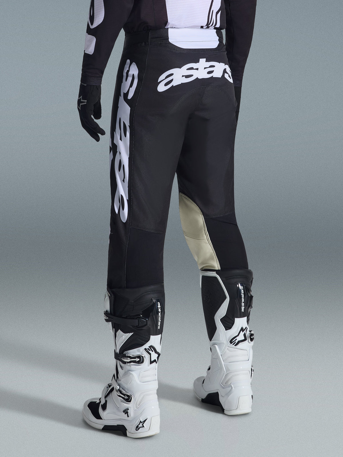Pantalon de motocross Alpinestars Racer Air Riway 2026, vue arrière, noir et blanc, avec logo 'astars' blanc sur l'assise et la jambe, empiècements en cuir crème à l'intérieur des genoux, porté avec un maillot et des bottes assortis.