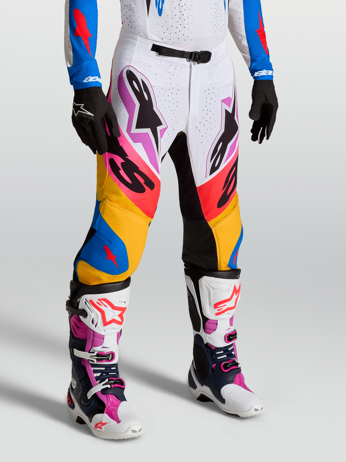 Alpinestars Supertech Dyna, pantalons de motocross pour homme, blancs et bleus, tissu rip-stop extensible et panneaux en cuir de chèvre, portés par un mannequin, équipement de course tout-terrain premium