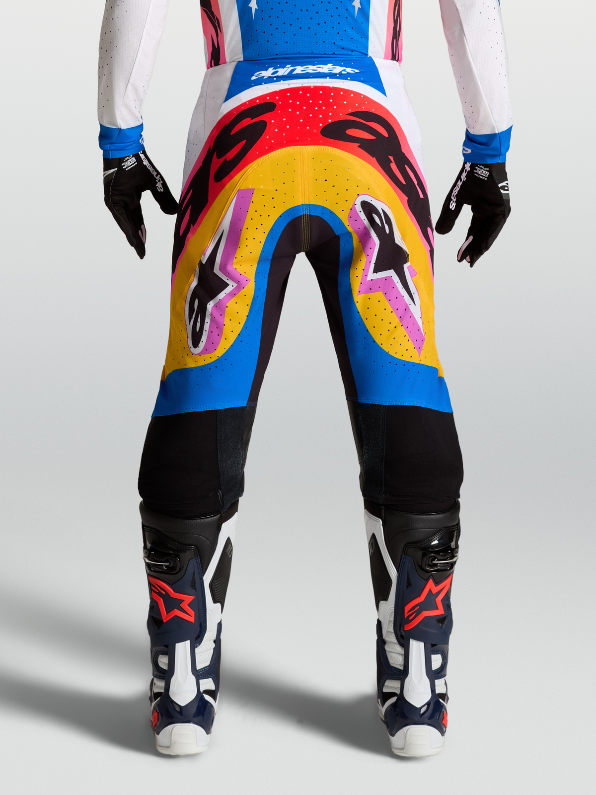 Pantalons Supertech Dyna Alpinestars, pantalons de motocross bleus et jaunes, design multicolore porté par un mannequin, matériau rip-stop extensible et léger